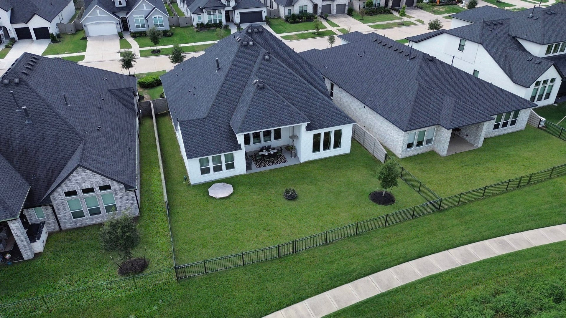 One final look from above showcases your home's premium waterfront lot, covered patio, and spacious backyard, where indoor comfort meets outdoor living against a beautiful lakeside backdrop.