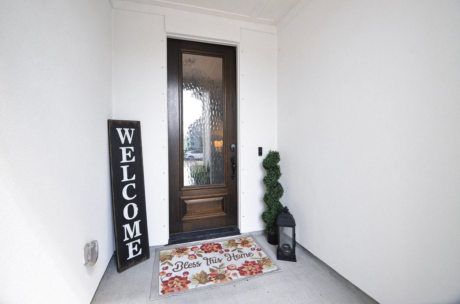Step through the elegant wood-and-glass front door, tucked beneath a covered entryway that offers a warm welcome for guests and the perfect spot for the Amazon deliveries to stay dry.