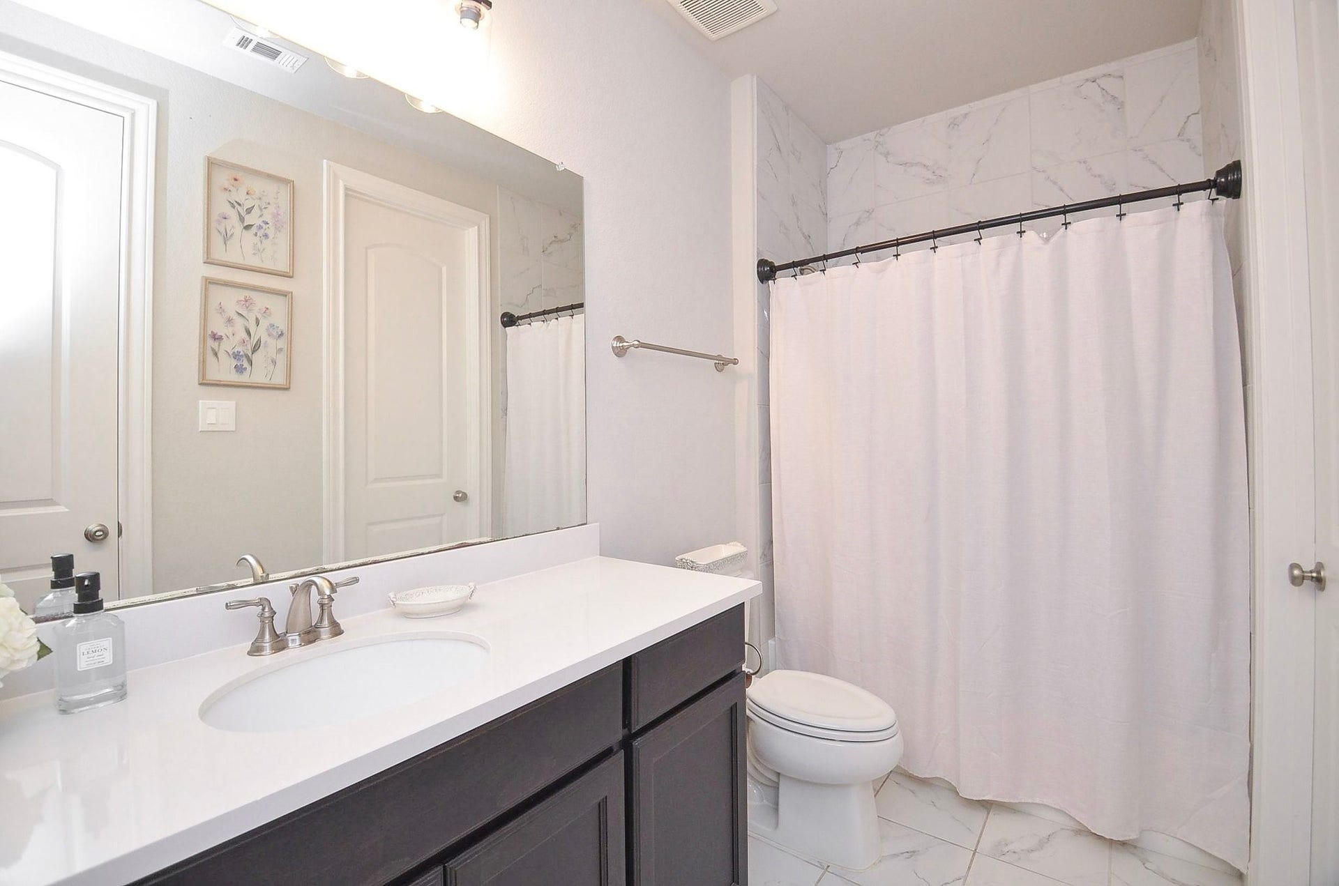 This private 11' x 6' bathroom features a spacious vanity, large mirror, and light, timeless finishes. Ample counter space and cabinetry keep everyday essentials neatly organized.  All bedrooms in this home offers generous-sized walk-in closets as well.