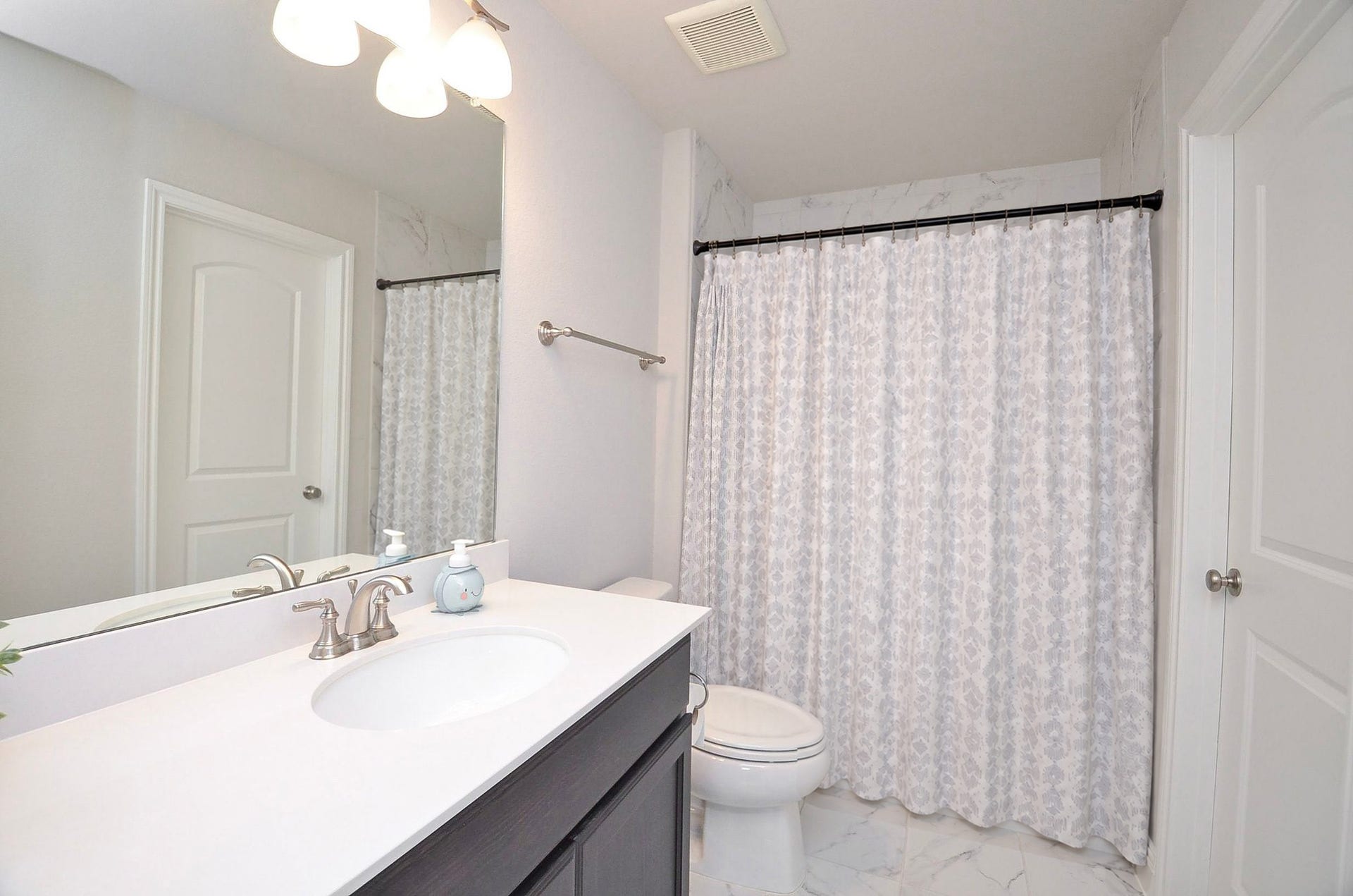 The en-suite bathroom is a bright 5' x 10' bathroom featuring a spacious vanity, ample storage, and a convenient shower/tub combination.