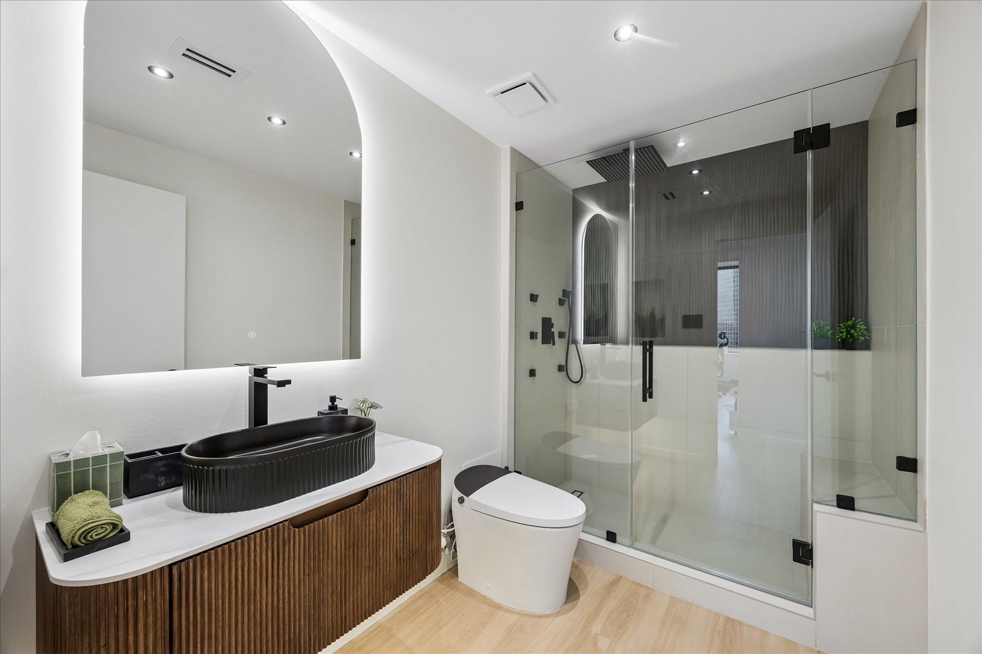 14 Greenway Plaza, #9R, Houston, TX 77046 Floating fluted vanity and illuminated mirror complement a glass enclosed shower with a bench.