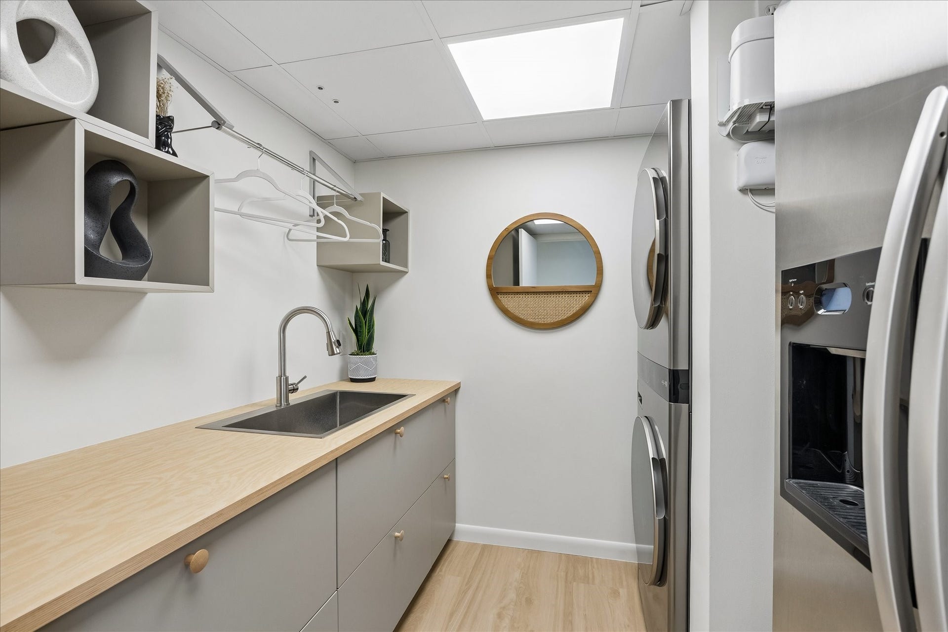 14 Greenway Plaza, #9R, Houston, TX 77046 Utility room combines a sink, long countertop, cabinetry and hanging space beside stacked LG washer/dryer appliances with remote app control. An extra side-by-side refrigerator provides additional cold storage.