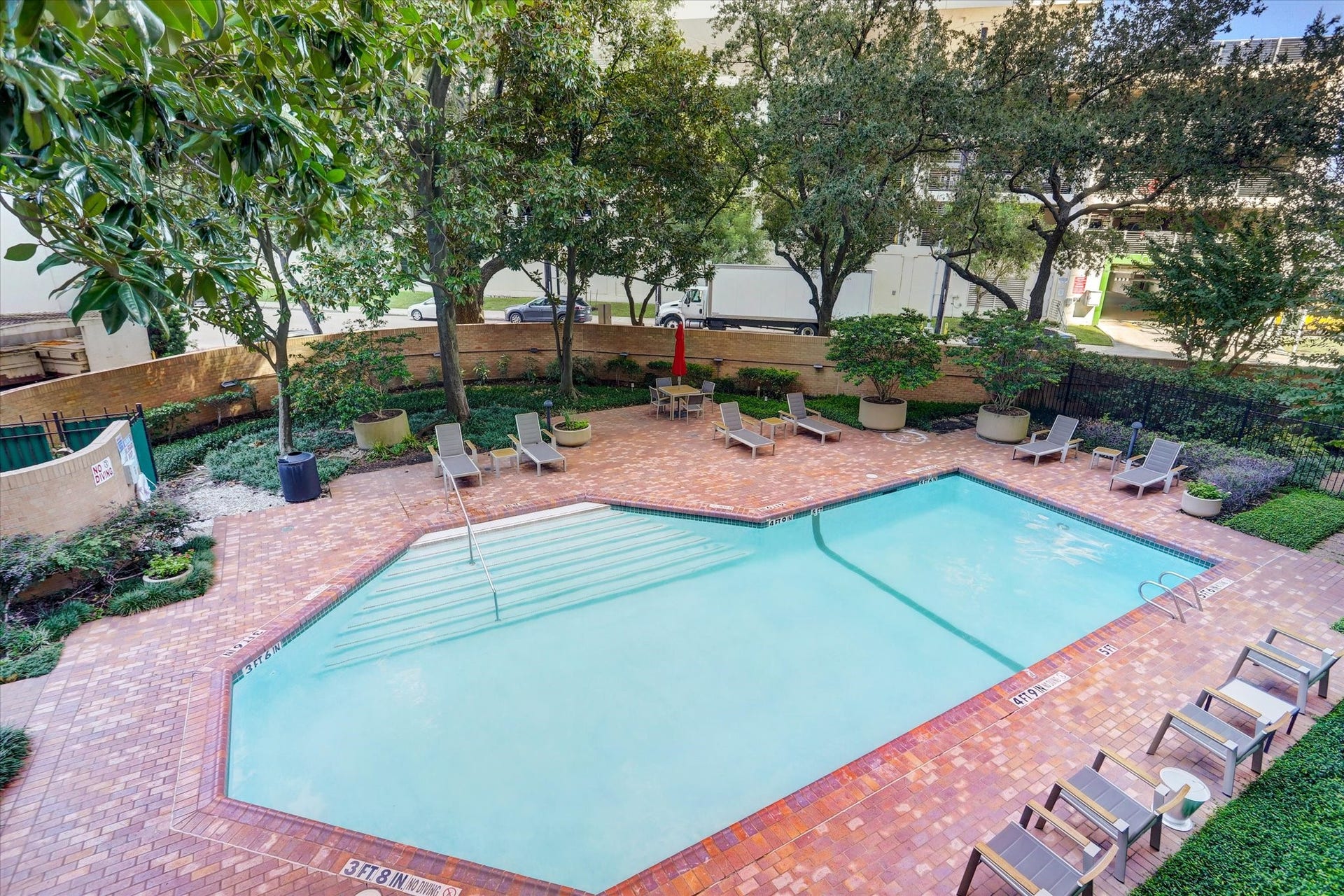 14 Greenway Plaza, #9R, Houston, TX 77046 A landscaped courtyard with a heated, temperature-controlled pool offers a relaxing outdoor escape, with a spacious brick terrace, poolside lounge seating and mature trees framing the setting.