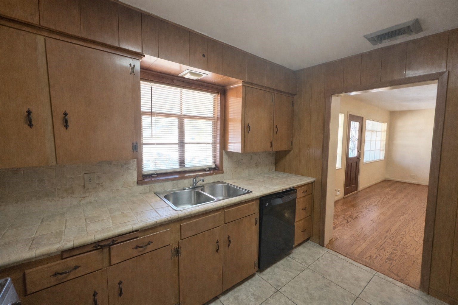Another view of kitchen. Neutral-colored ceramic tile counter tops and backsplash.  Window provides natural light and tile flooring for easy maintenance.