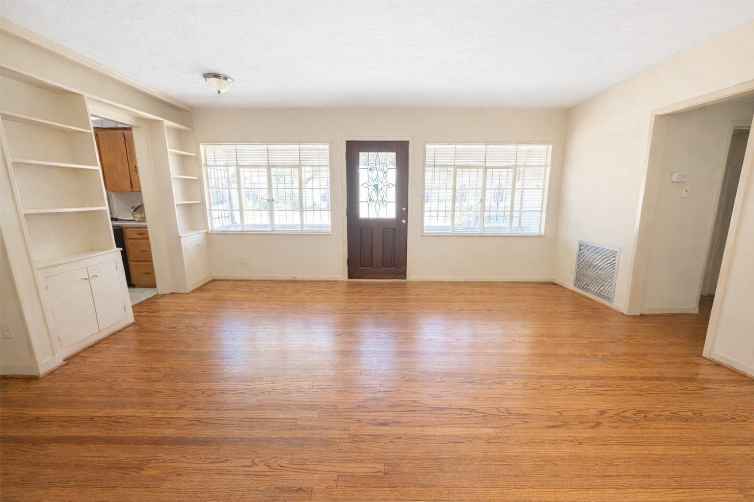 View of front entrance/living room.  Large windows and leaded glass door offer plenty of natural light and welcoming feel.