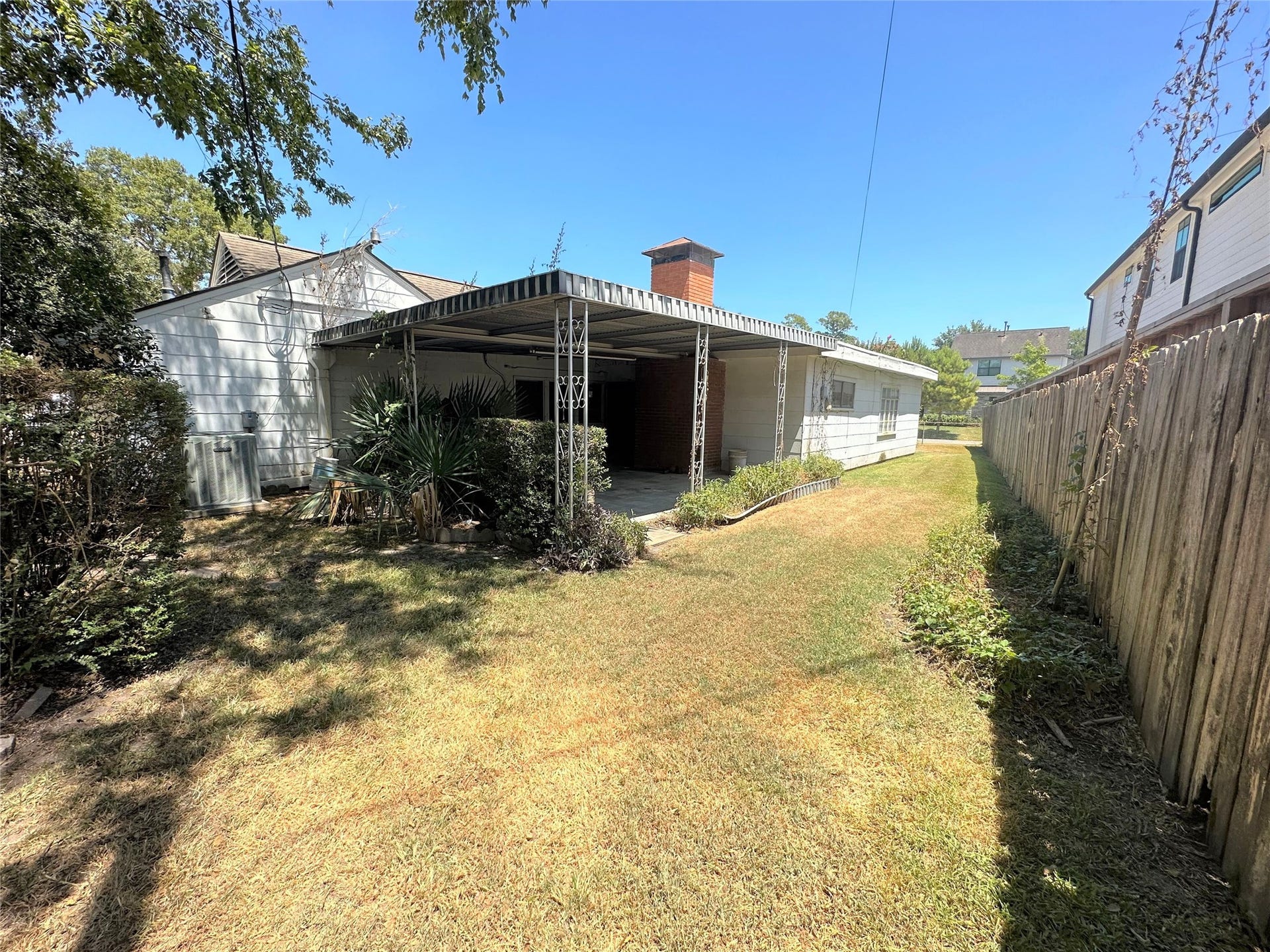 View of the fully-fenced backyard of home and the large covered patio.