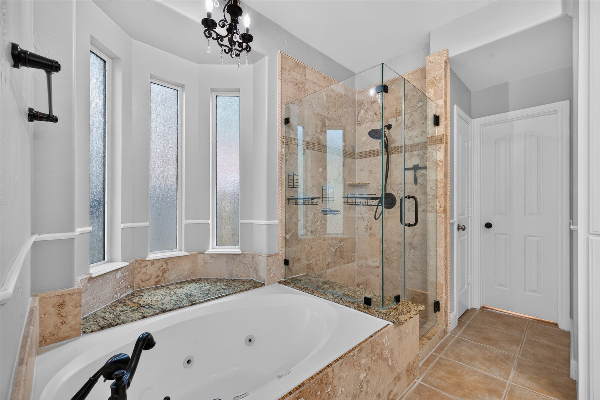 13611 Cottage Arbor Court, Sugar Land, TX 77498 Another view of the primary bath showcases the jetted soaking tub framed by tall privacy windows and the spacious frameless glass shower with beautiful stone tile detailing.