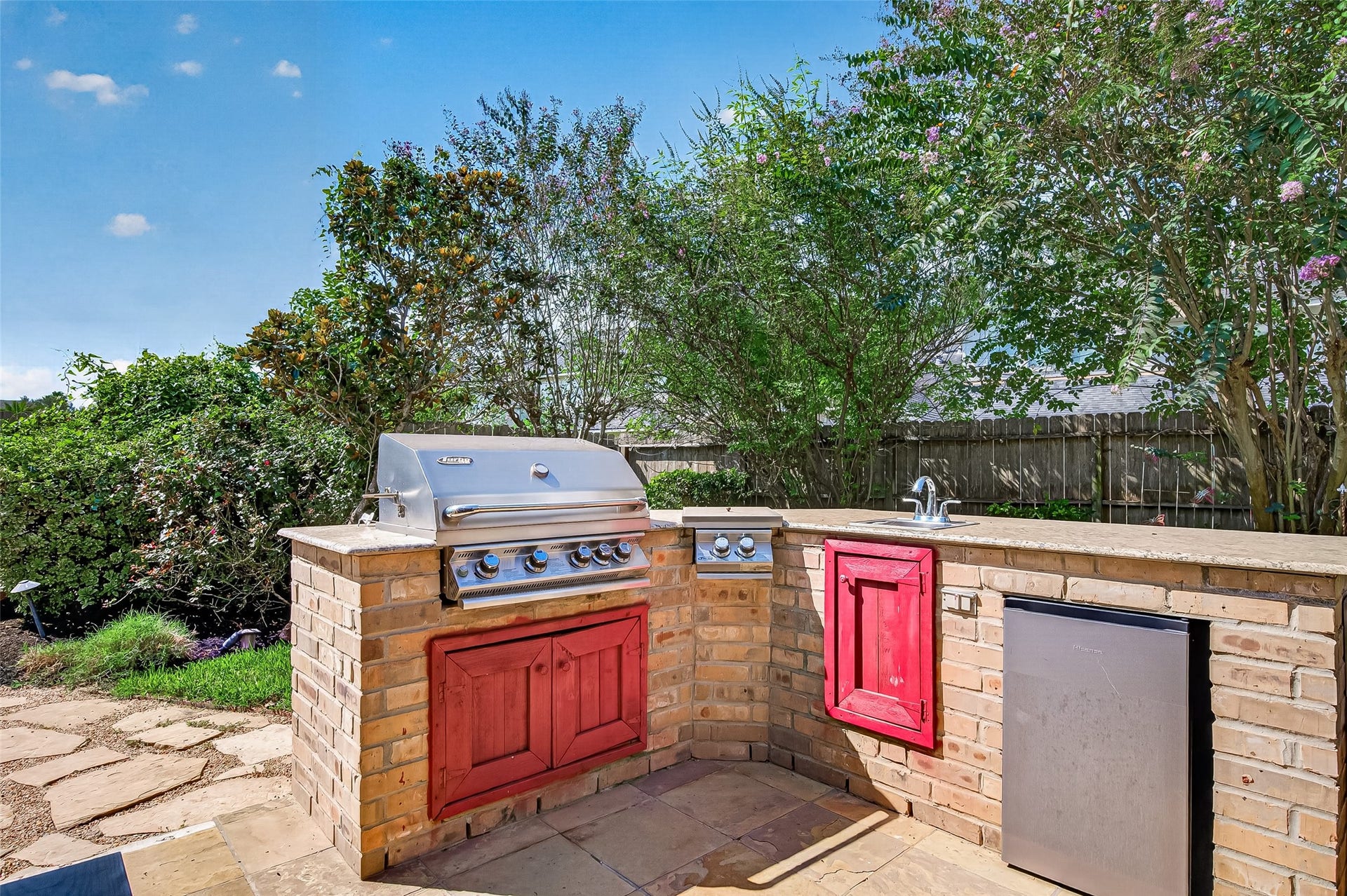13611 Cottage Arbor Court, Sugar Land, TX 77498 Built-in outdoor kitchen featuring a stainless-steel grill, side burner, sink, generous granite counter space, storage, and outdoor refrigerator; ideal for effortless backyard entertaining.