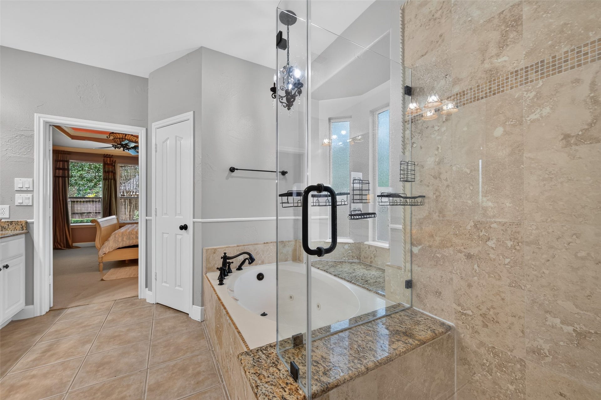 13611 Cottage Arbor Court, Sugar Land, TX 77498 Closer view of the primary bath highlights the oversized frameless glass shower with floor-to-ceiling stone tile, alongside the jetted soaking tub with granite surround.