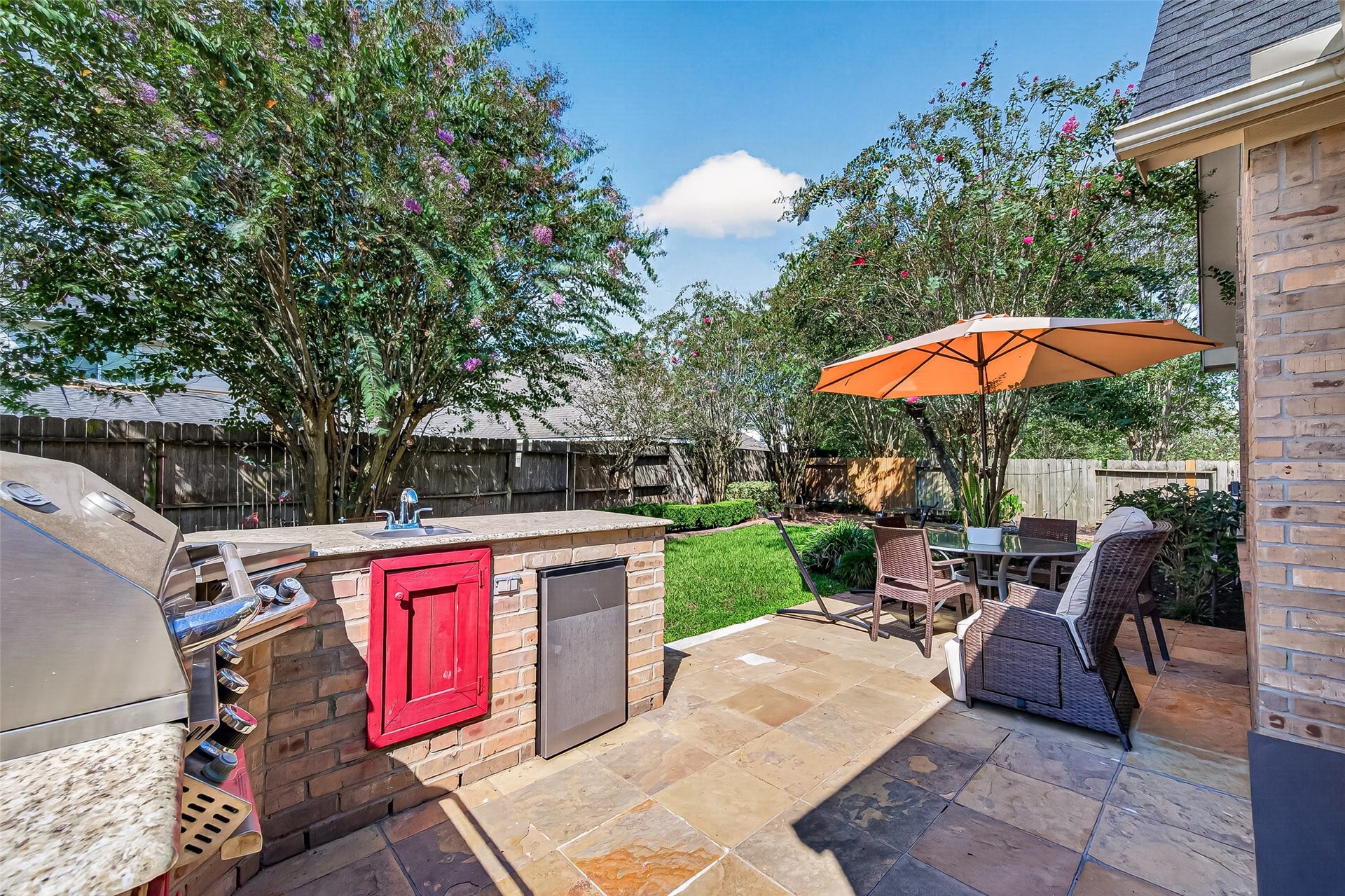 13611 Cottage Arbor Court, Sugar Land, TX 77498 Inviting outdoor patio featuring a built-in outdoor kitchen with grill and sink, spacious dining and seating areas, and views of the beautifully landscaped backyardperfect for outdoor entertaining.