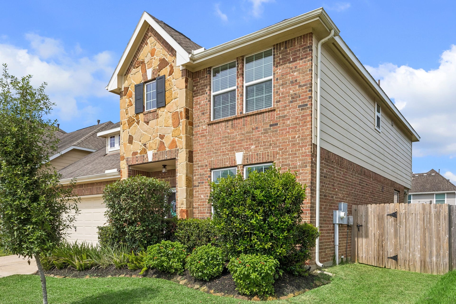 4702 Alluvial Circle, Alvin, TX 77511 Charming two-story home with a brick and stone facade, featuring lush landscaping and a fenced side yard. Ideal for comfortable family living.