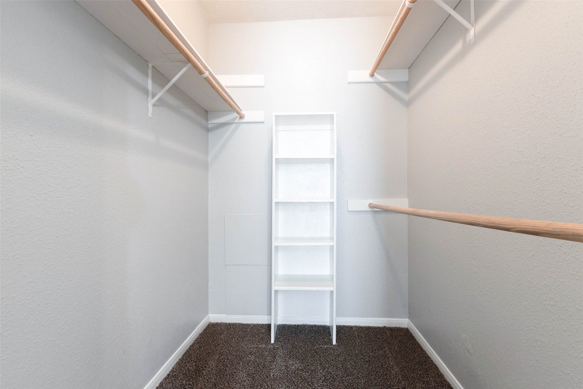 Spacious walk-in closet with built-in shelving, multiple hanging rods, and room to keep clothing and accessories organized.