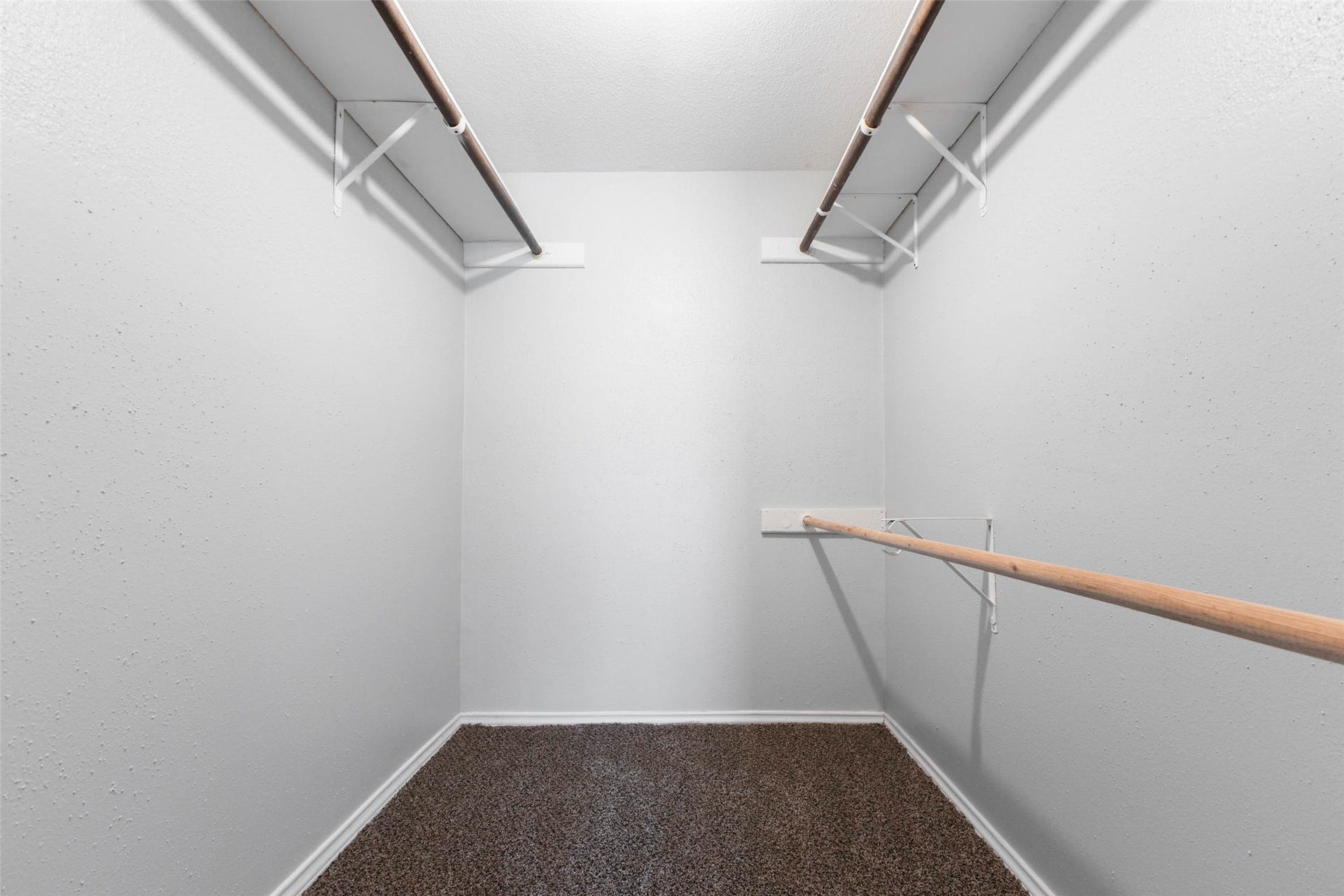 Generously sized walk-in closet with shelving and hanging rods on both sides for organized storage.