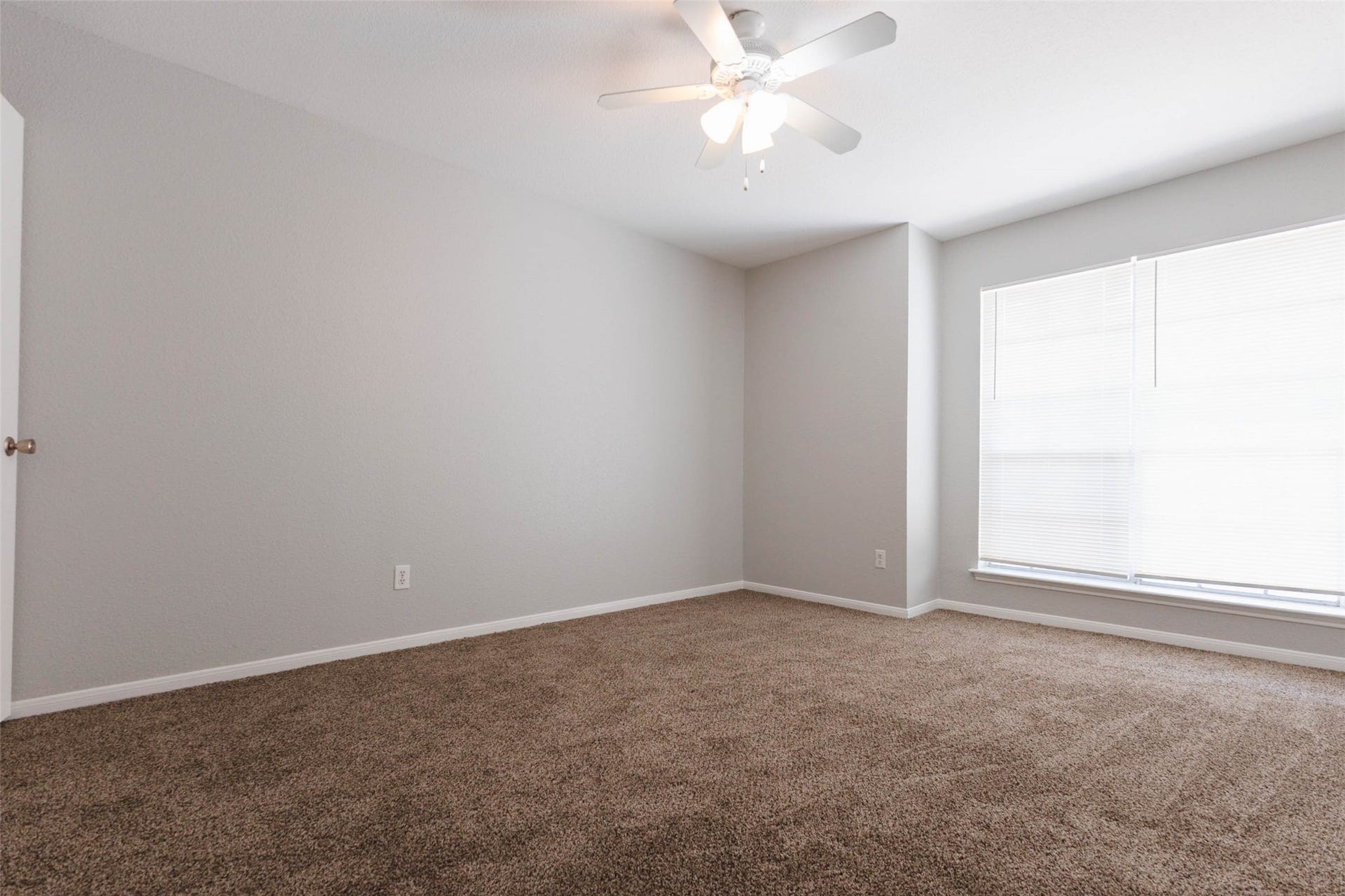 Additional bedroom view showcasing neutral finishes, comfortable proportions, and natural light from the window.