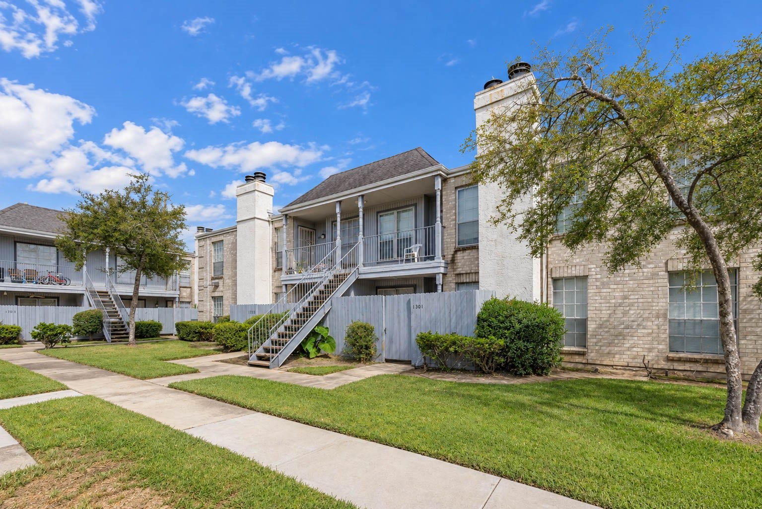 Another view of the community's inviting exterior, showcasing mature shade trees, open green spaces, and walkways.