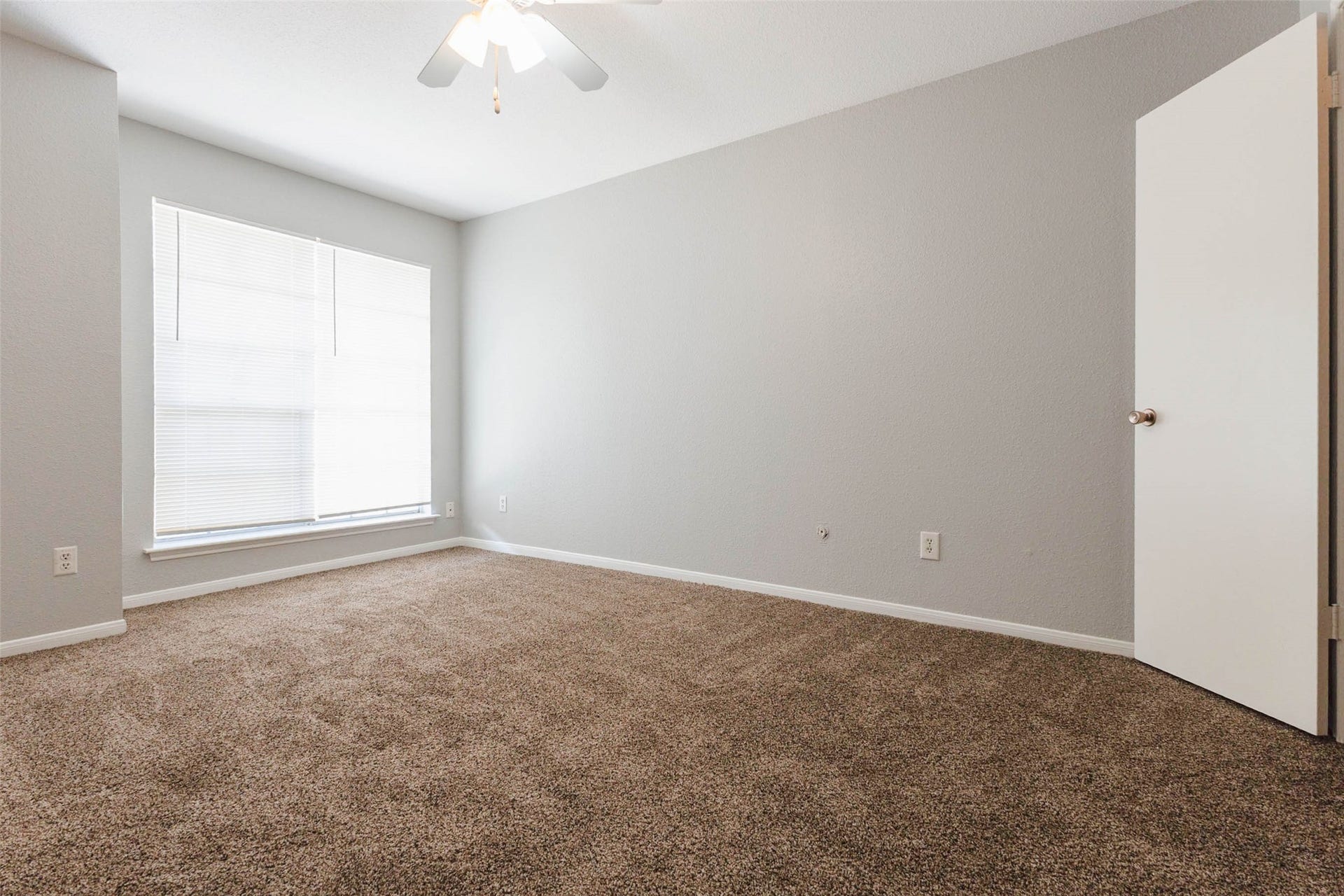 Another view of the bedroom highlighting its generous floor space, natural lighting, and versatile furniture arrangement options.