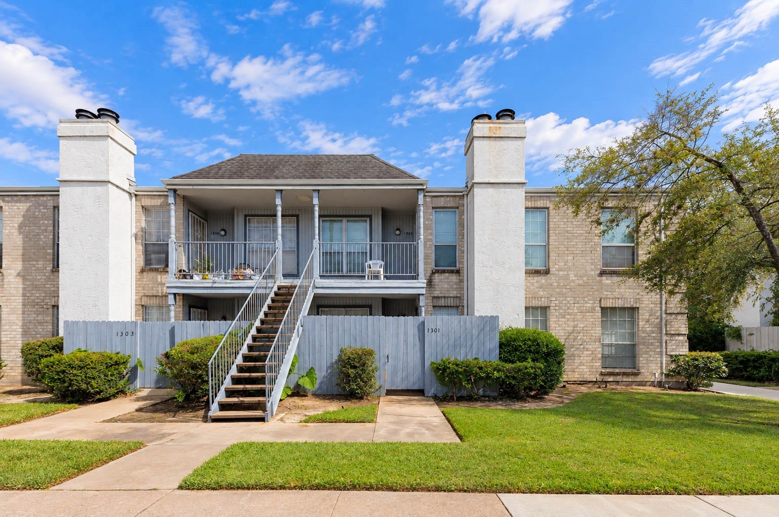 Attractive two-story residential building featuring covered porches, exterior stairway access, and well-maintained landscaping.
