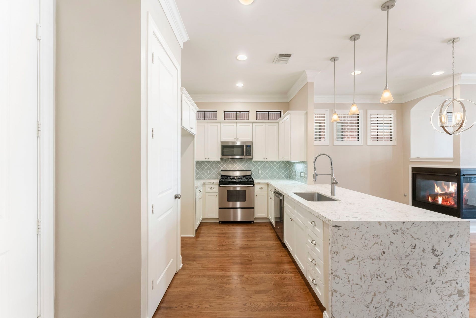 24 Riva Row, Spring, TX 77380 Crisp white shaker cabinetry, an arabesque tile backsplash, and transom windows above make this kitchen bright and timeless.