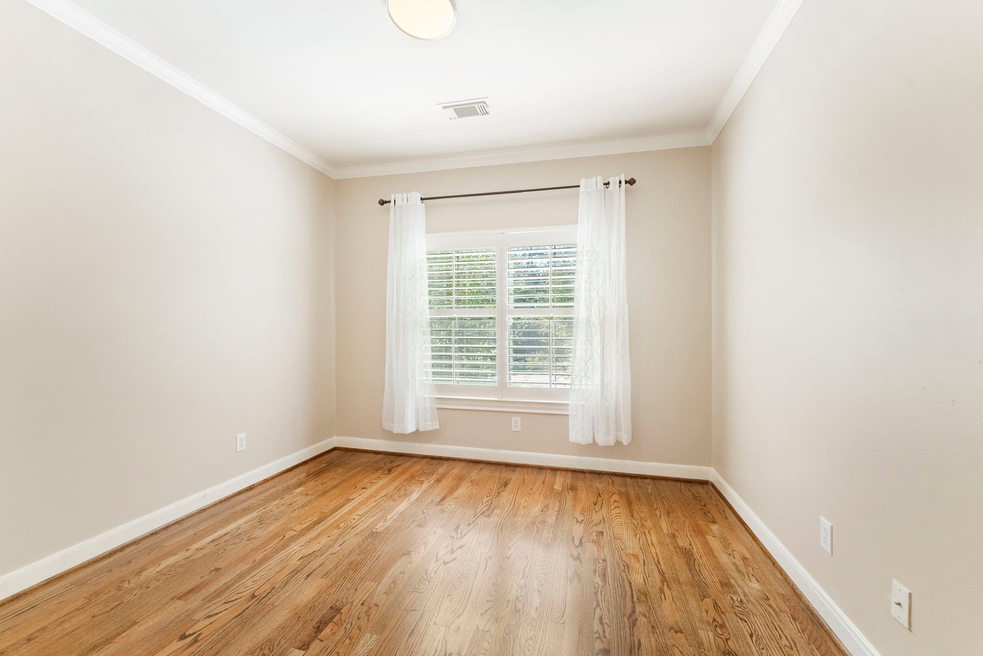 24 Riva Row, Spring, TX 77380 A bright secondary bedroom on the second floor with hardwood floors, crown molding, and plantation shutters.