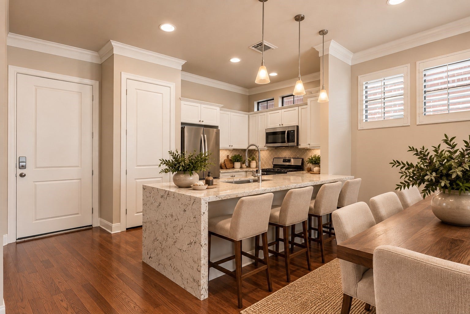 24 Riva Row, Spring, TX 77380 A waterfall-edge island with breakfast bar seating anchors this bright kitchen, featuring white cabinetry, a gas range, and stainless microwave. Virtually staged; refrigerator not included.