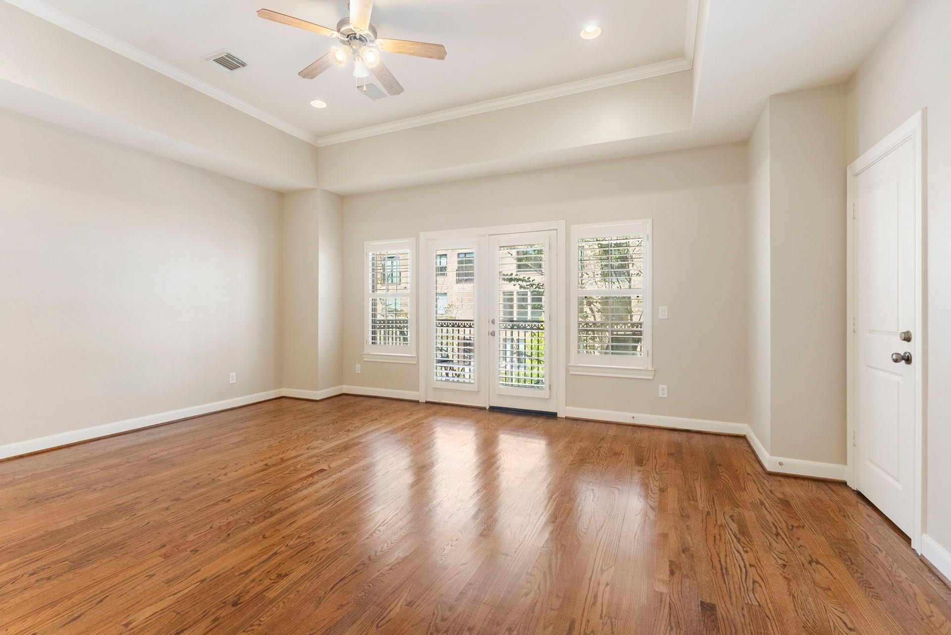 24 Riva Row, Spring, TX 77380 A tray ceiling, rich hardwoods, and French doors to a private balcony make this primary bedroom stand out.