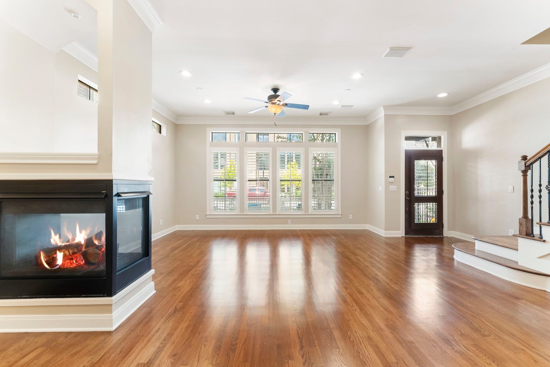 24 Riva Row, Spring, TX 77380 Sunlight streams through four tall windows with transoms, reflecting off gleaming hardwood floors.