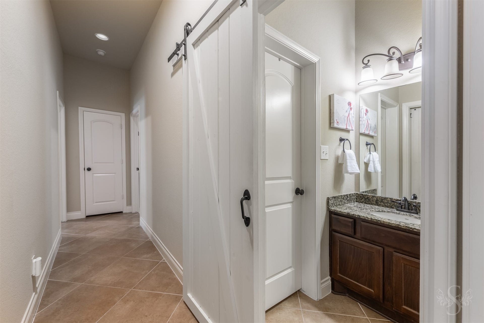 5219 Kenton Place Lane, Fulshear, TX 77441 A sliding barn door adds character to the hallway and offers a stylish way to close off the adjoining bath. A granite vanity with richly stained cabinetry continues the homes elegant finishes.
