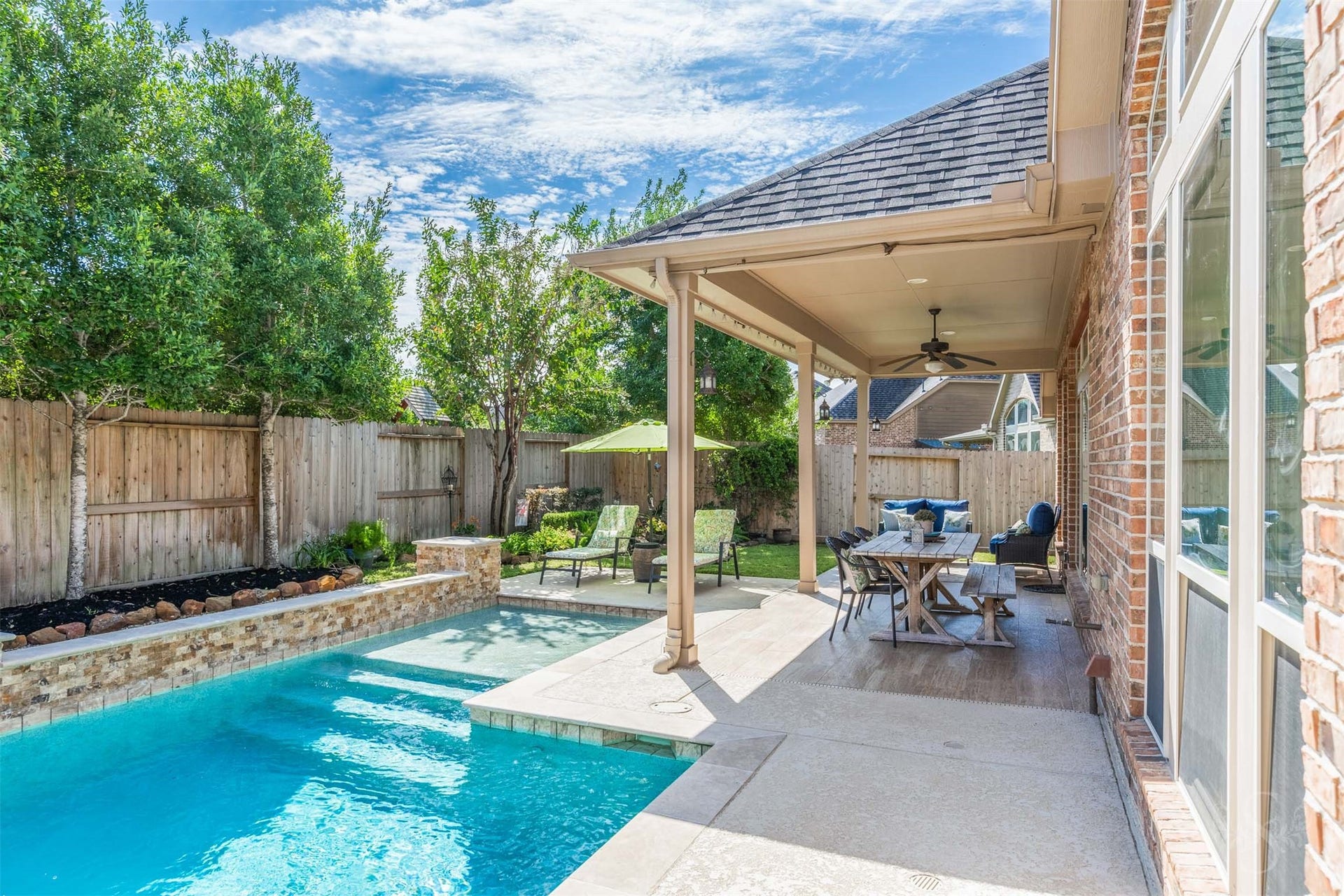 5219 Kenton Place Lane, Fulshear, TX 77441 The covered patio offers an inviting setting for outdoor dining and relaxed conversation overlooking the sparkling pool. Beautiful landscaping and generous space for seating make this backyard retreat a wonderful place to gather with family and friends.