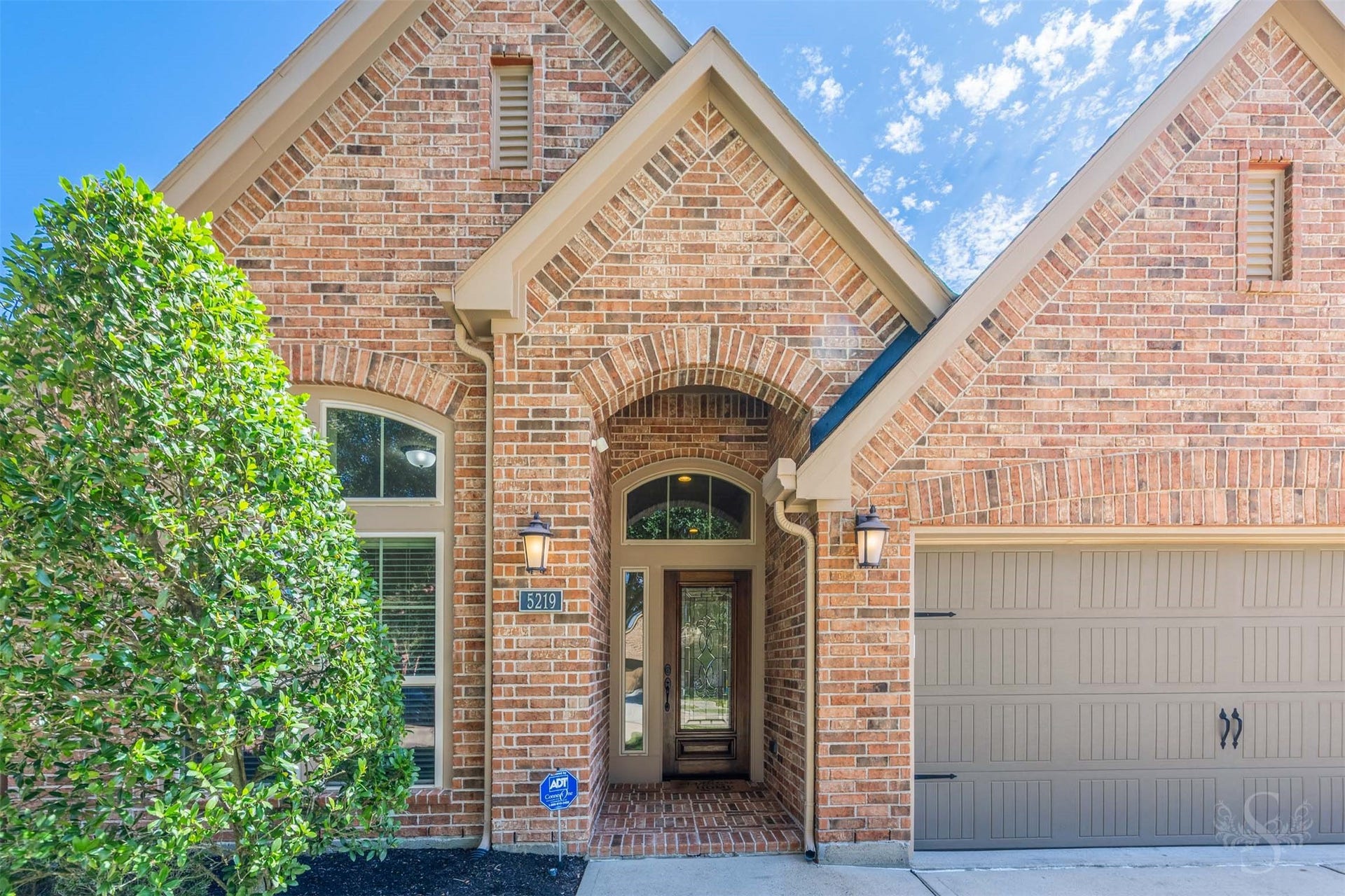 5219 Kenton Place Lane, Fulshear, TX 77441 A dramatic brick arch frames the sheltered entrance, where a decorative glass front door, coordinating sidelight & arched transom create an elegant introduction. The brick porch welcomes you inside to an inviting entry crowned by tray ceilings.