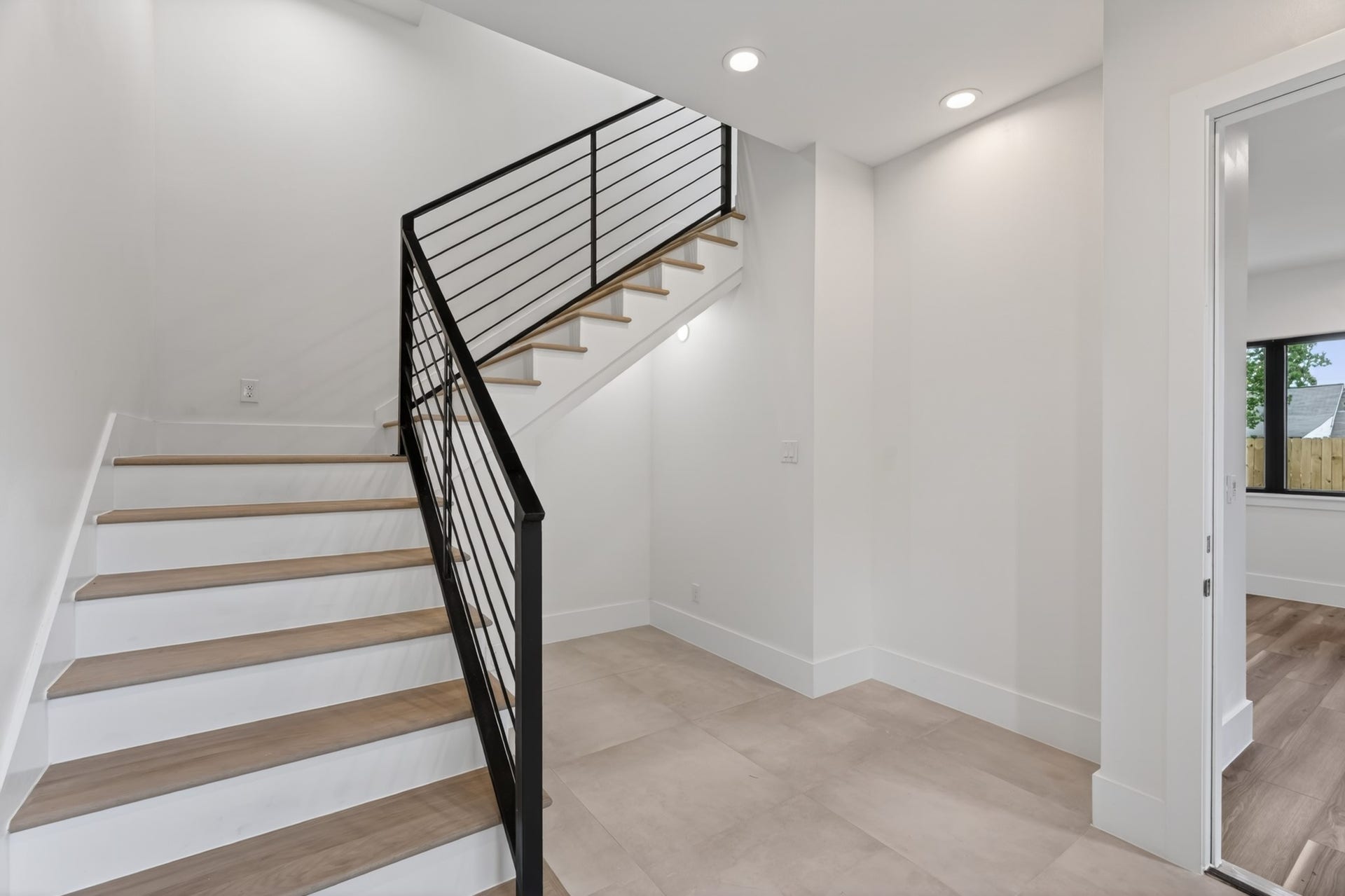 Bright and inviting foyer featuring high ceilings, abundant natural light, and an open layout. The modern staircase with sleek railing creates a striking architectural focal point and a grand first impression