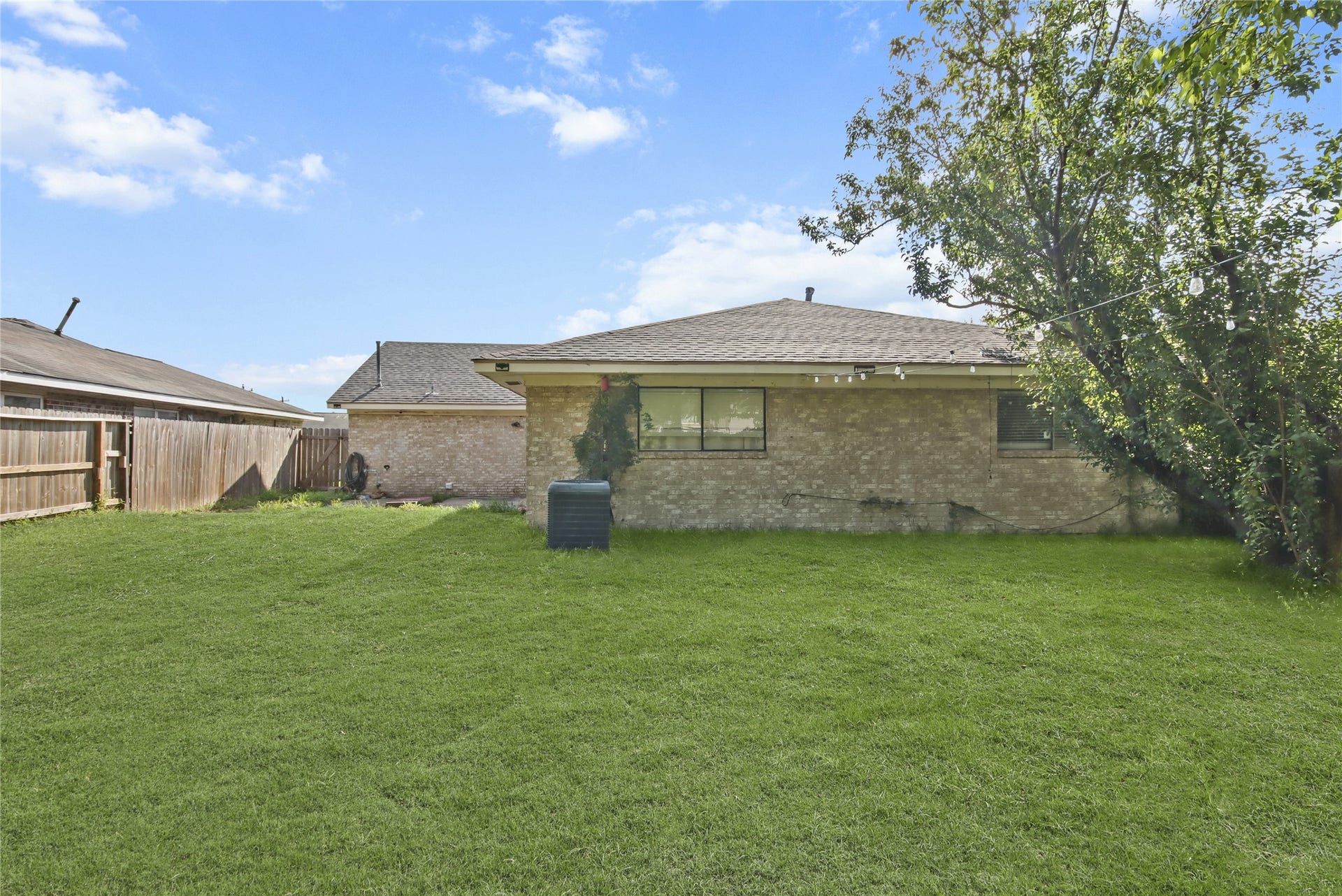 910 Centerwood Drive, Houston, TX 77013 A large grassy backyard provides plenty of room to relax or entertain, framed by mature trees and a privacy fence.