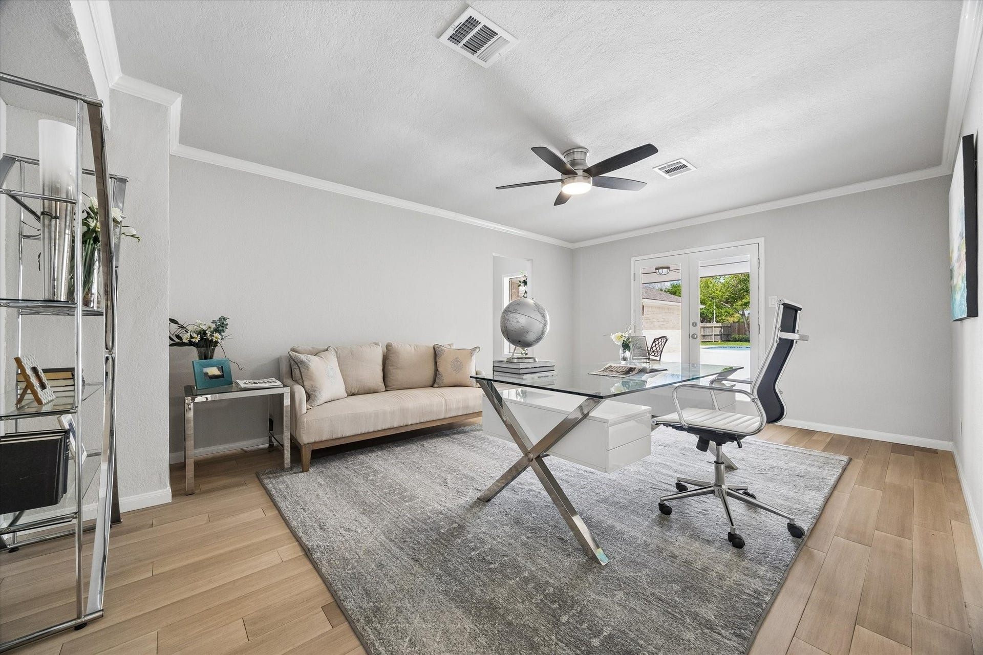 3122 Peach Tree Lane, Missouri City, TX 77459 This bright, modern home office features French doors with a view of the backyard. Neutral tones and a ceiling fan enhance the airy atmosphere, perfect for productivity.