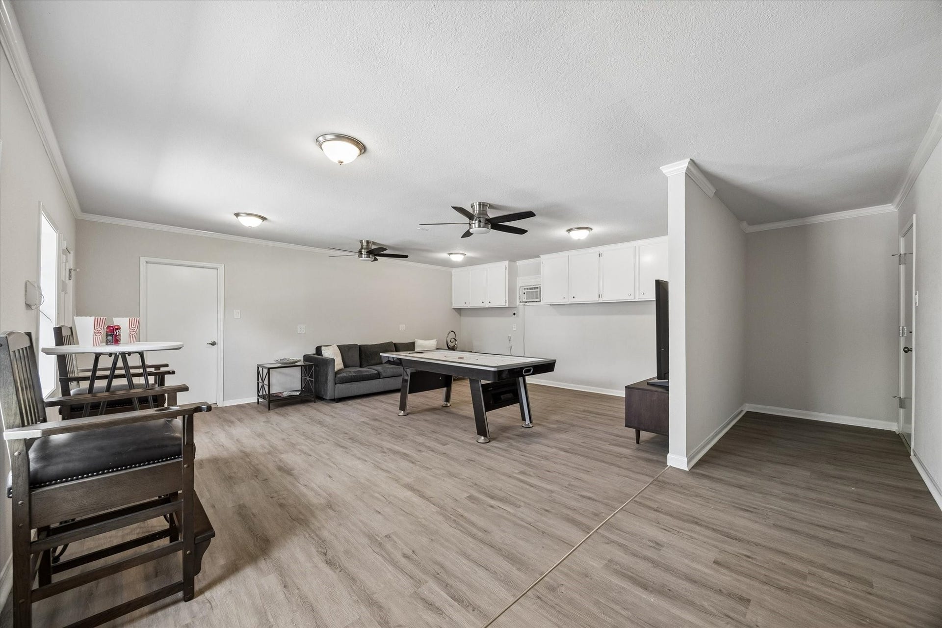 3122 Peach Tree Lane, Missouri City, TX 77459 This photo showcases a spacious, open-concept game room with light wood flooring. The room has modern lighting and ceiling fans, creating a bright and inviting atmosphere.
