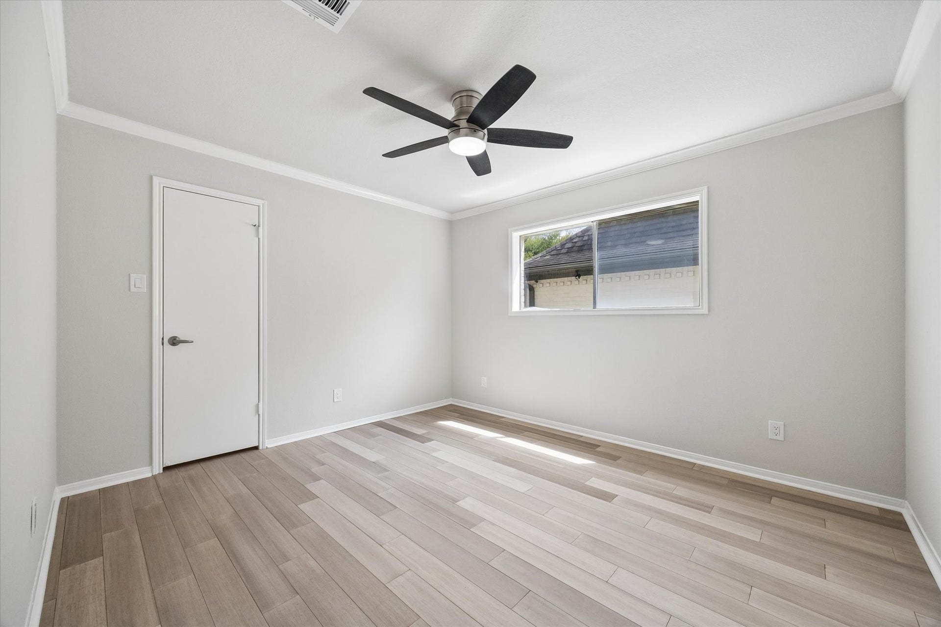 3122 Peach Tree Lane, Missouri City, TX 77459 Bright, spacious secondary bedroom with light wood flooring, neutral walls, a ceiling fan, and a large window for natural light.