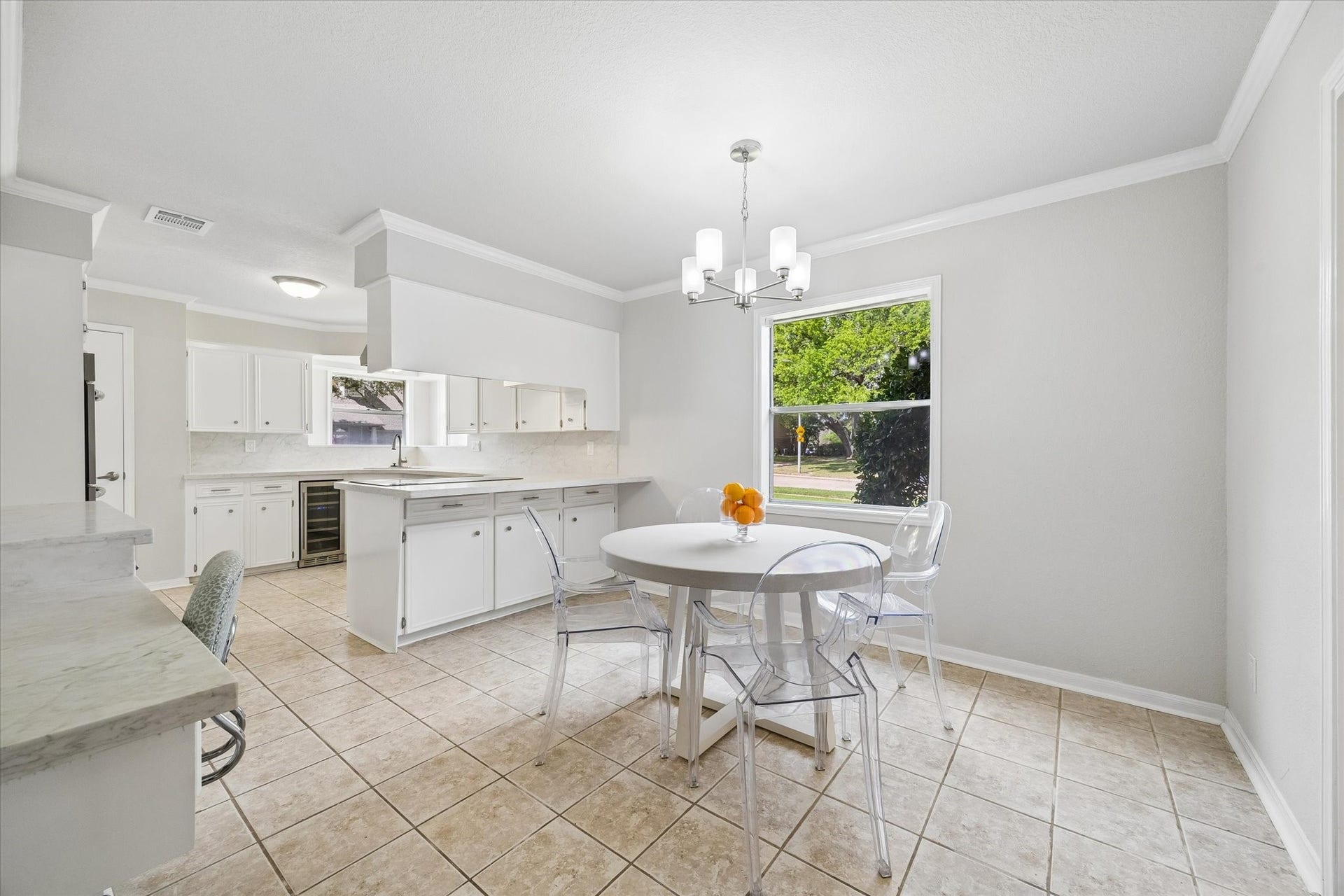 3122 Peach Tree Lane, Missouri City, TX 77459 This bright kitchen features white cabinetry, a central island, and a cozy breakfast area. Large windows provide plenty of natural light, while tiled floors add a clean, modern touch.