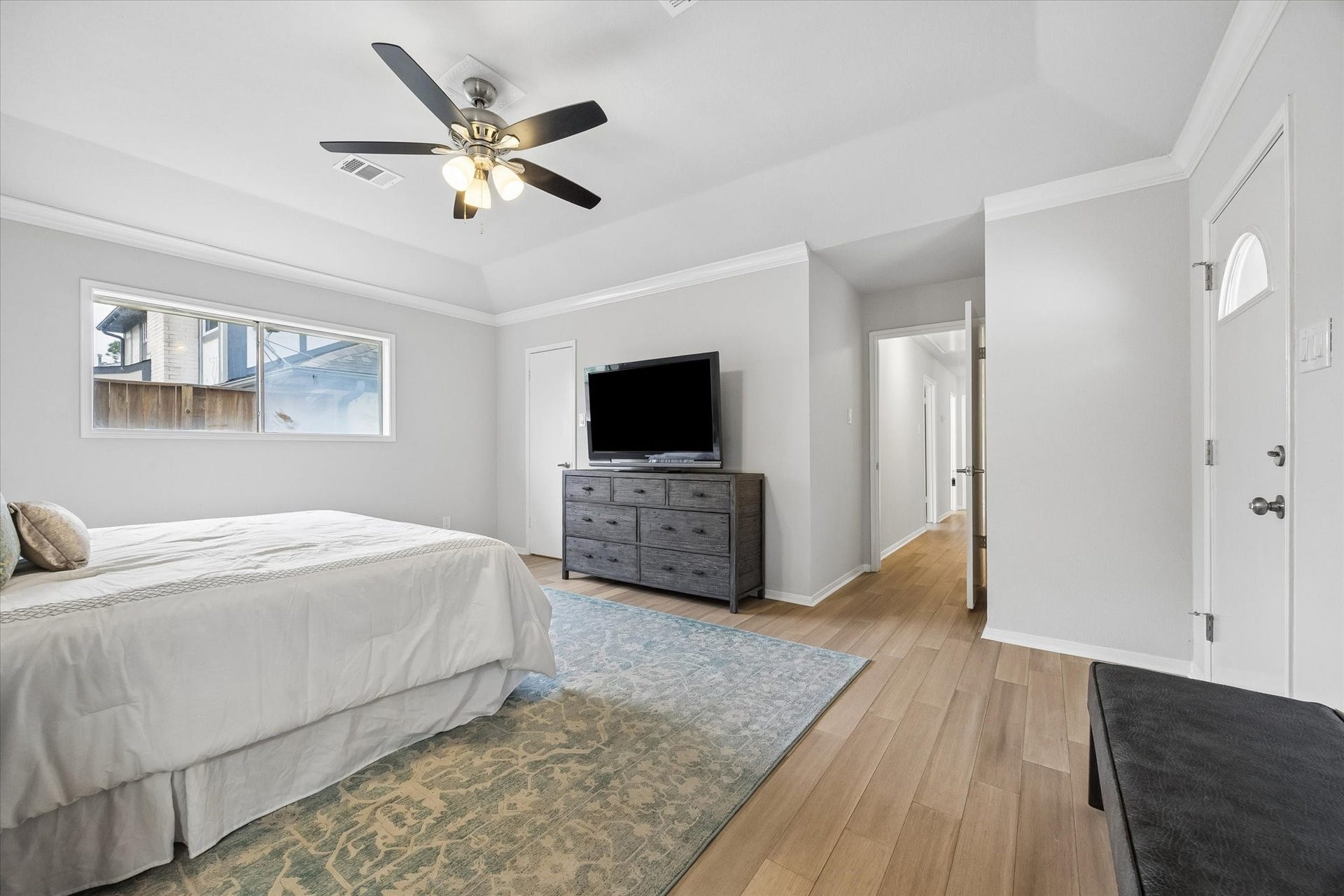 3122 Peach Tree Lane, Missouri City, TX 77459 This spacious primary bedroom features a large window for natural light, a ceiling fan, and light wood flooring.