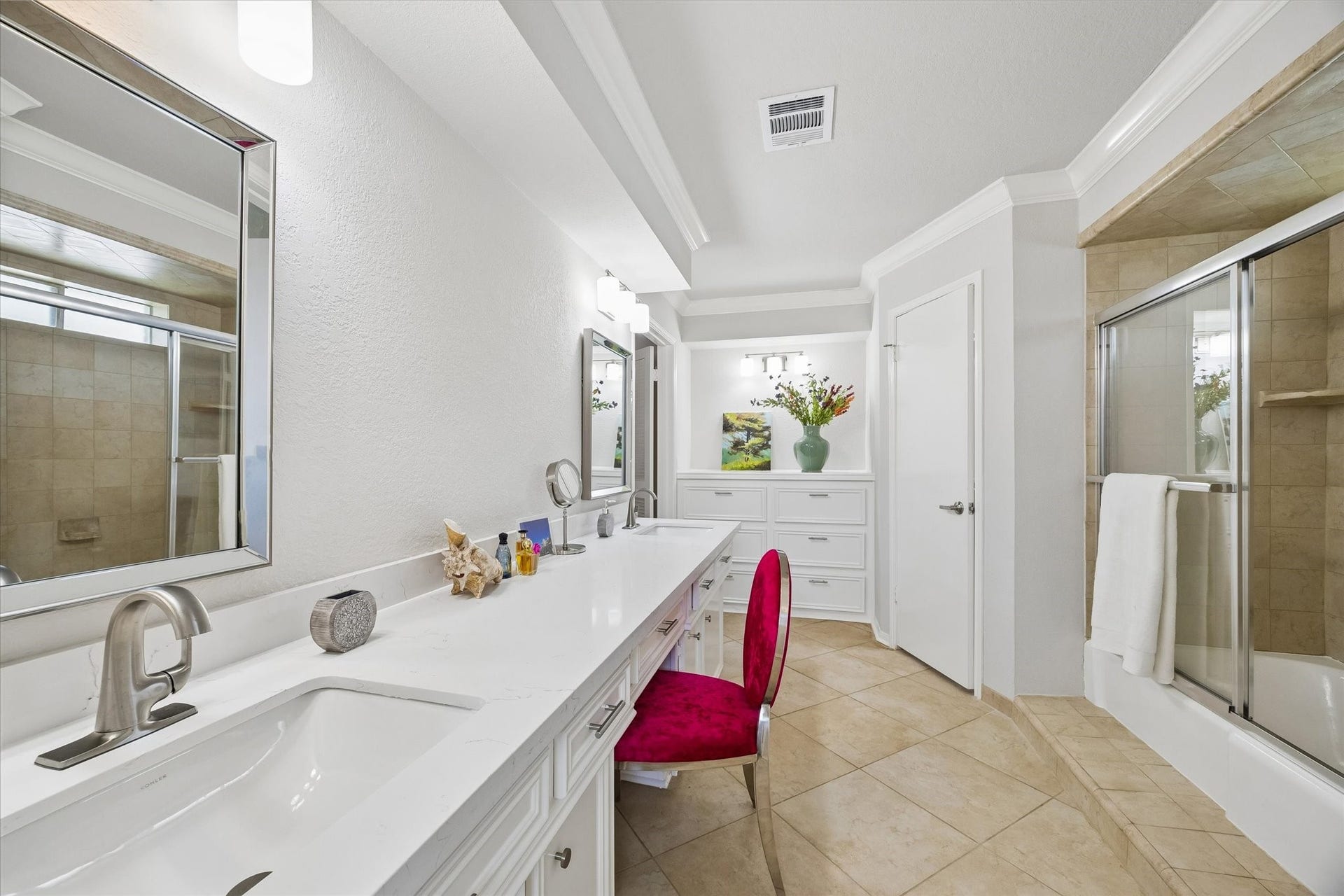 3122 Peach Tree Lane, Missouri City, TX 77459 This bright and spacious primary bathroom features a double vanity with modern fixtures, a large mirrors, and elegant tile flooring. The room includes a shower-tub combo with glass doors, ample cabinetry for storage, and a stylish seating area.