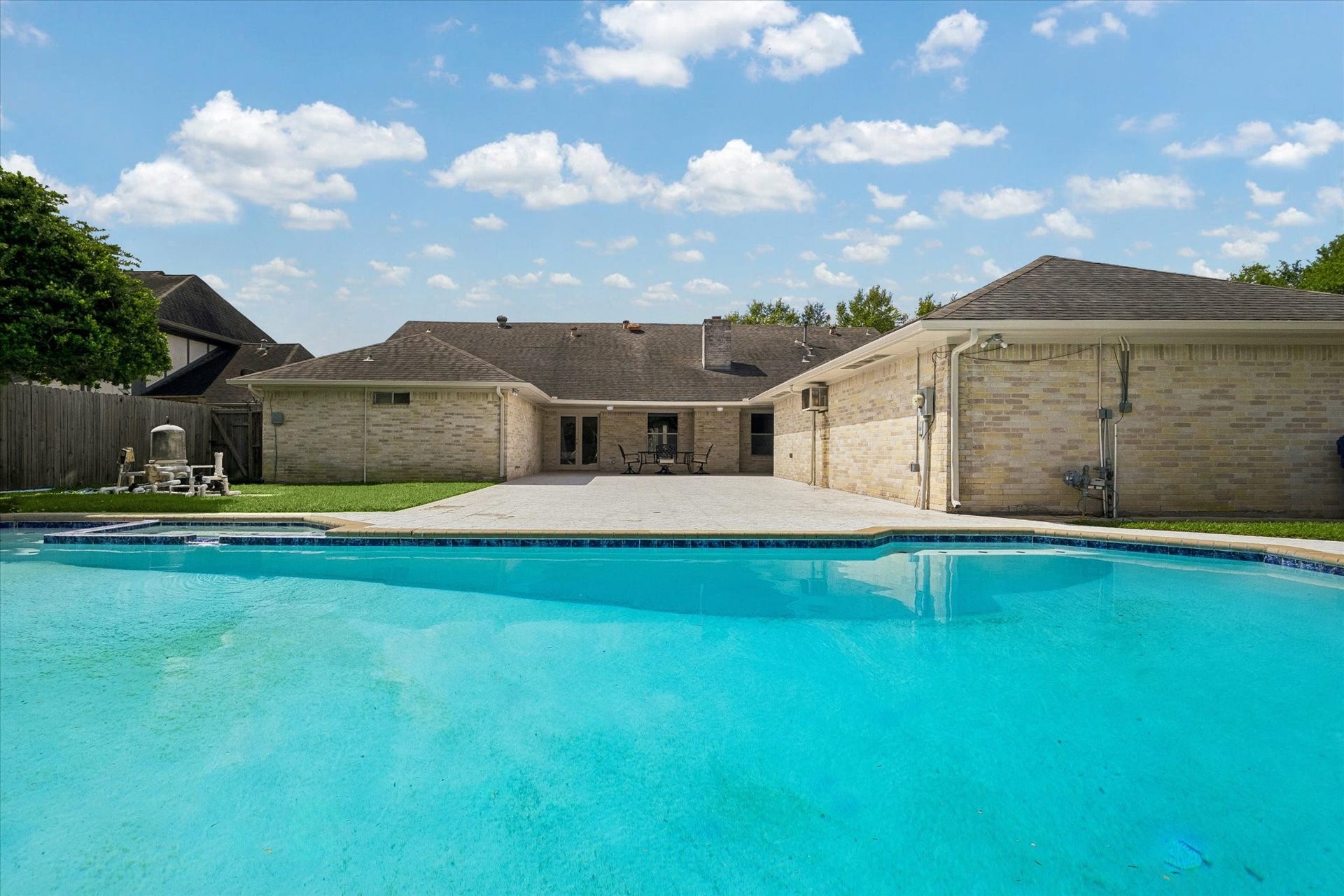 3122 Peach Tree Lane, Missouri City, TX 77459 This photo showcases a spacious backyard with a refreshing in-ground pool, surrounded by a well-maintained patio area. The brick exterior provides a classic look, offering ample space for outdoor activities and relaxation.