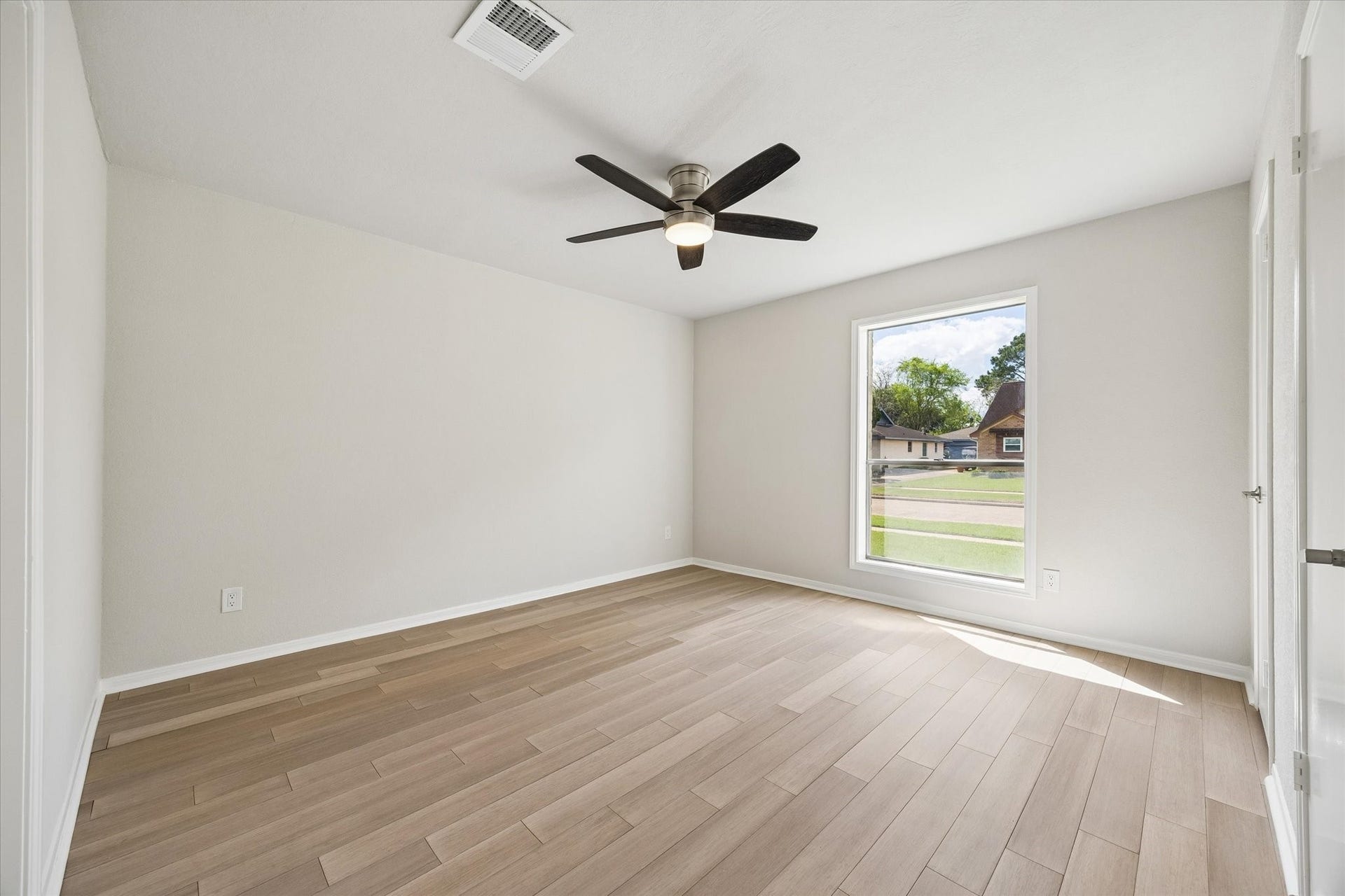 3122 Peach Tree Lane, Missouri City, TX 77459 This secondary bedroom features a modern ceiling fan, light wood flooring, and a large window that provides plenty of natural light and a view of the neighborhood. The neutral walls offer a versatile backdrop for any decor style.