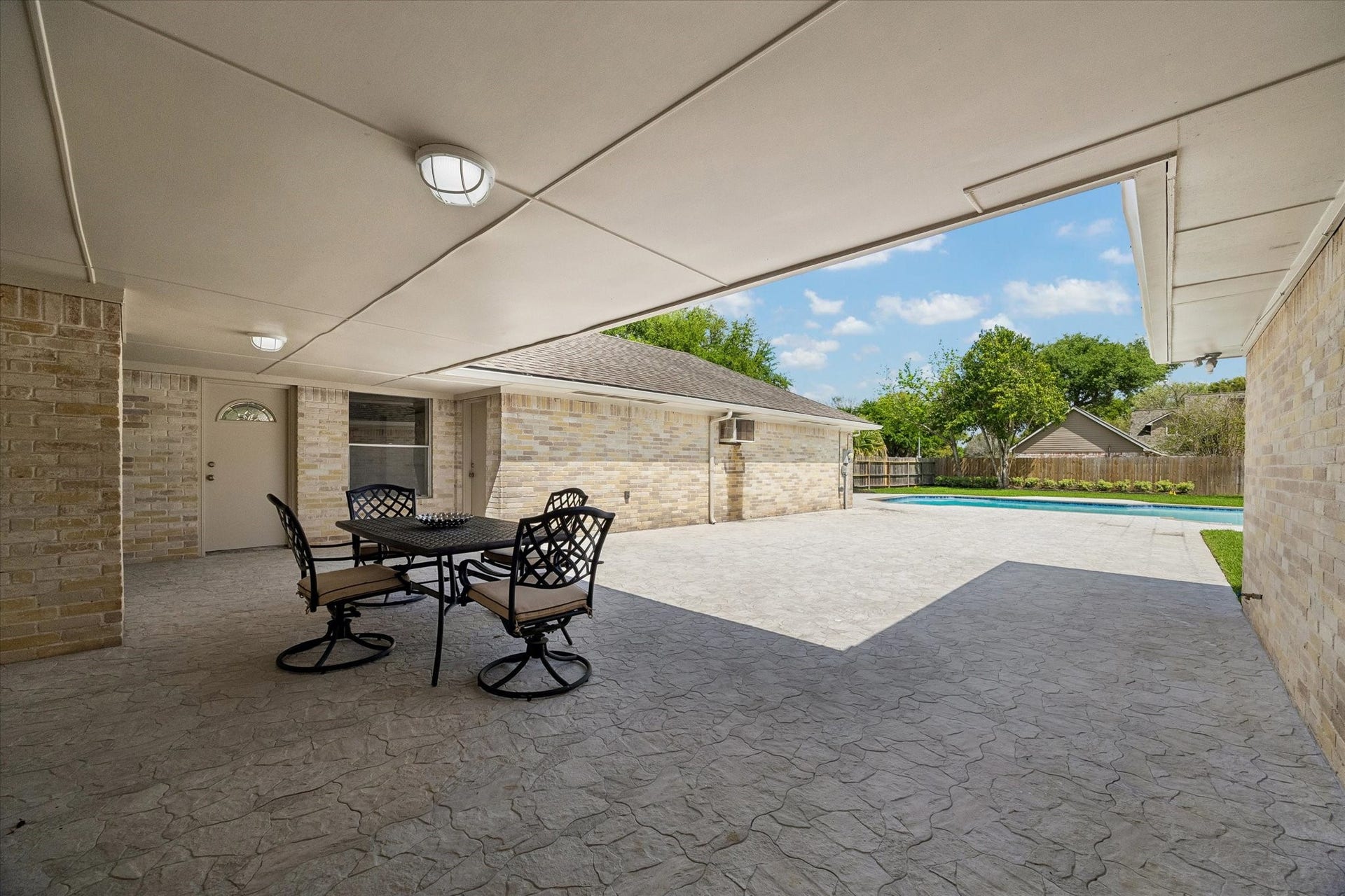 3122 Peach Tree Lane, Missouri City, TX 77459 This photo shows a spacious covered patio with outdoor seating, offering a view of a well-maintained backyard featuring a swimming pool and lush greenery. Perfect for outdoor entertaining and relaxation.