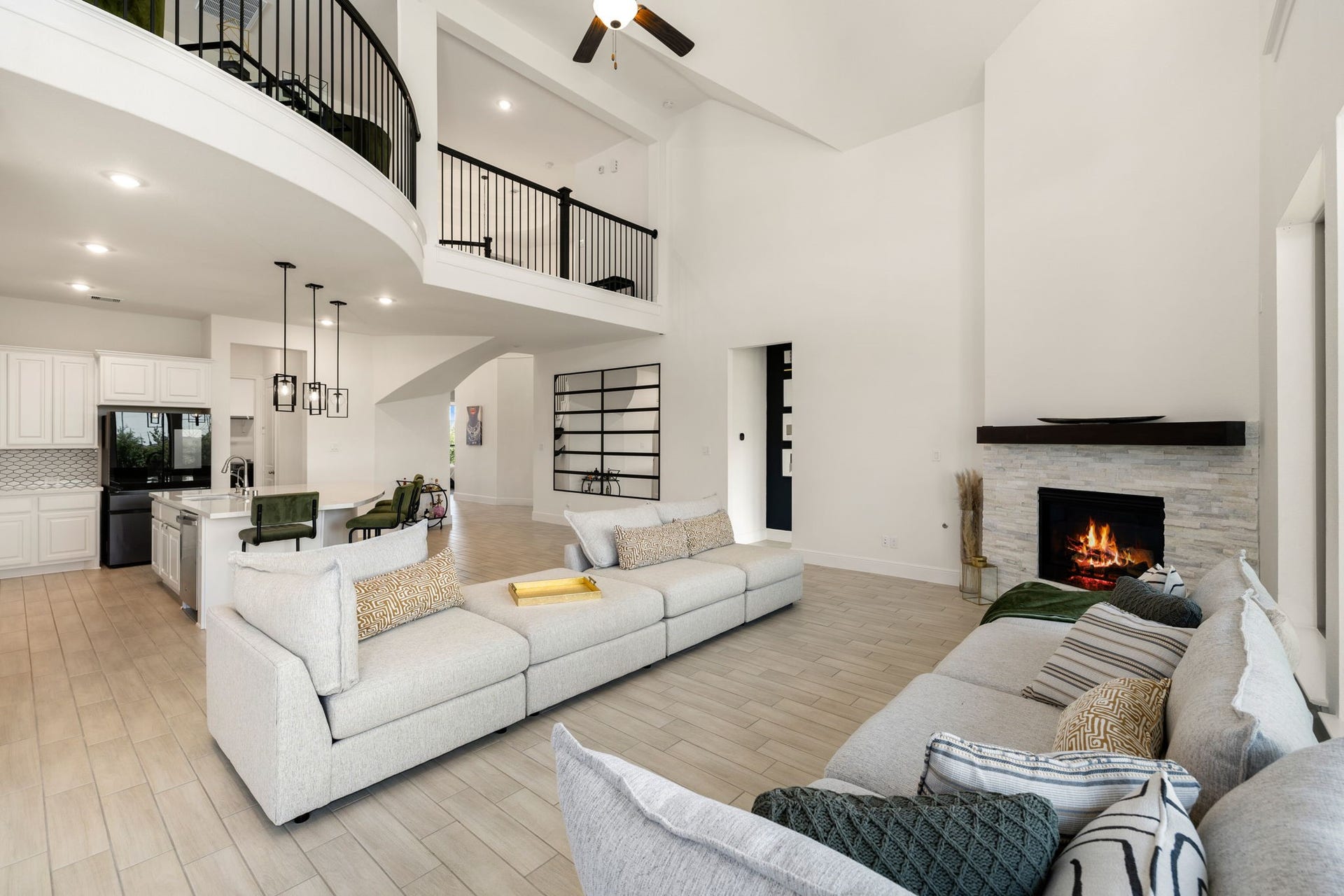 6903 Shoreline View Drive, Katy, TX 77493 Open-concept kitchen overlooking a cozy fireplace, complemented by natural light and a sweeping staircase!