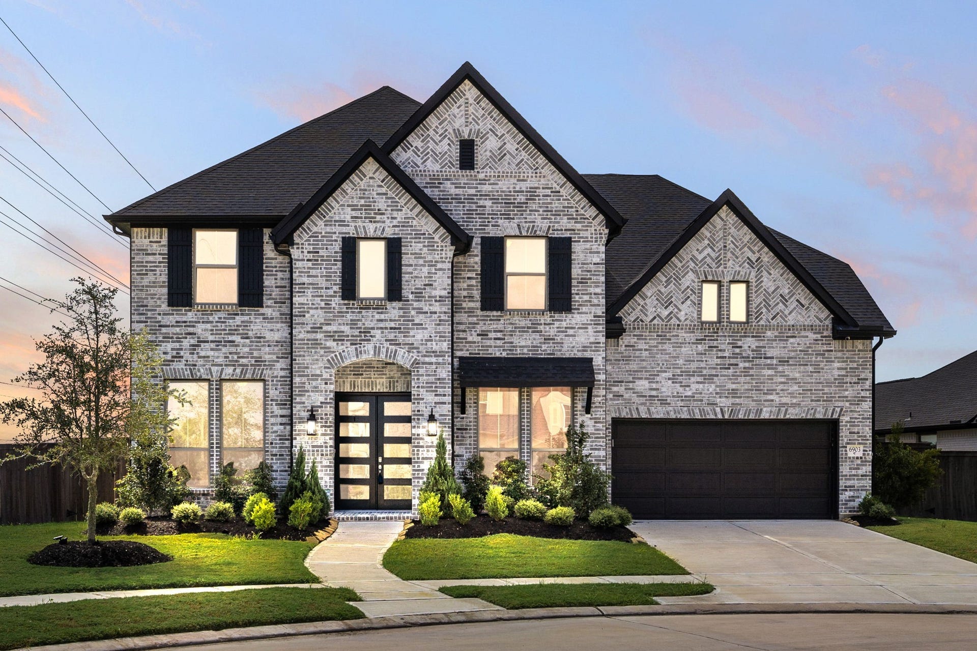 6903 Shoreline View Drive, Katy, TX 77493 Modern facade, featuring a spacious driveway, elegant landscaping, and a welcoming, glass-paneled front door!