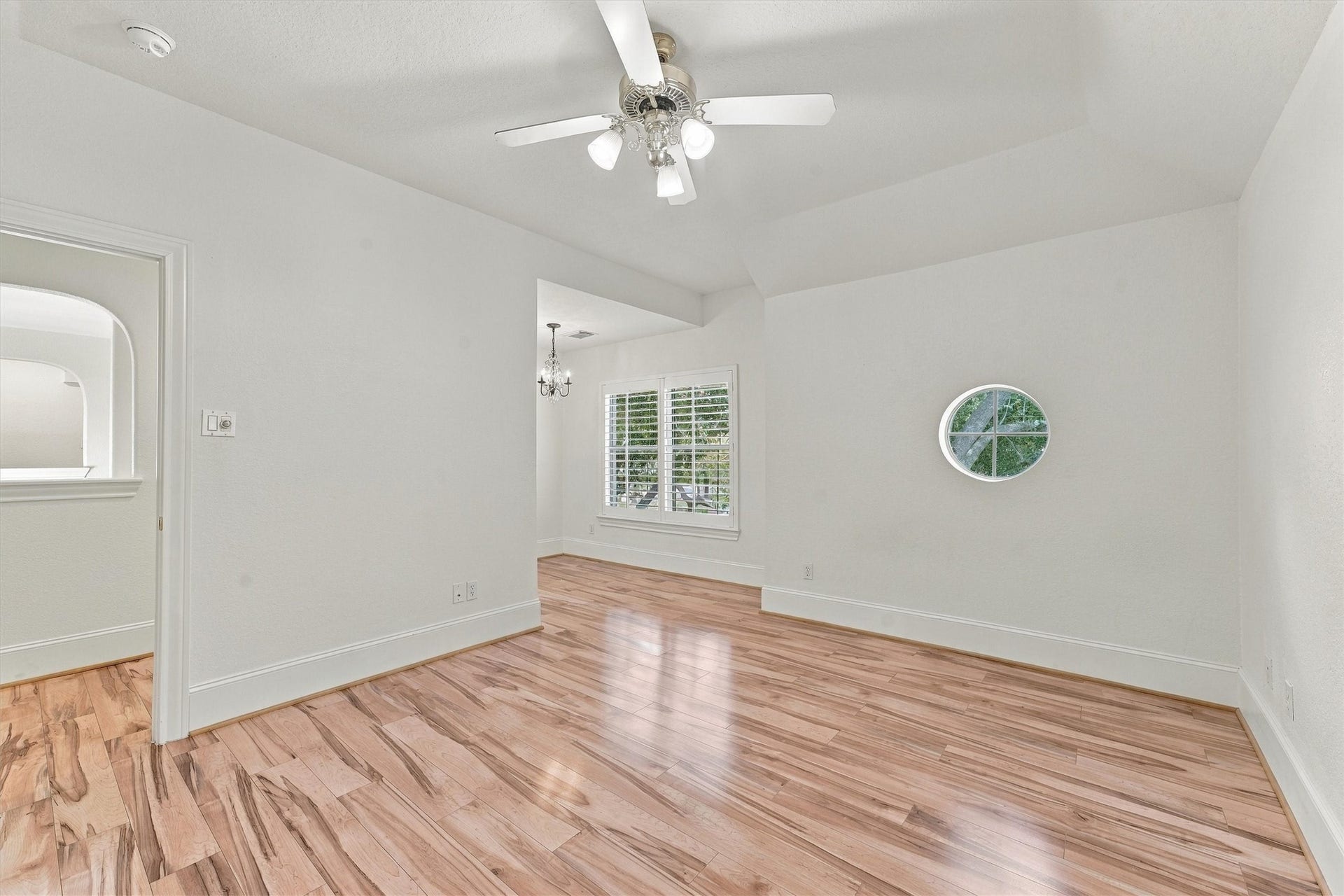 22415 Elizabeth Place Court, Katy, TX 77494 Bedroom three - Upstairs bedroom with sitting area, ceiling fan, wood flooring, round accent window, and chandelier with plantation shutters.