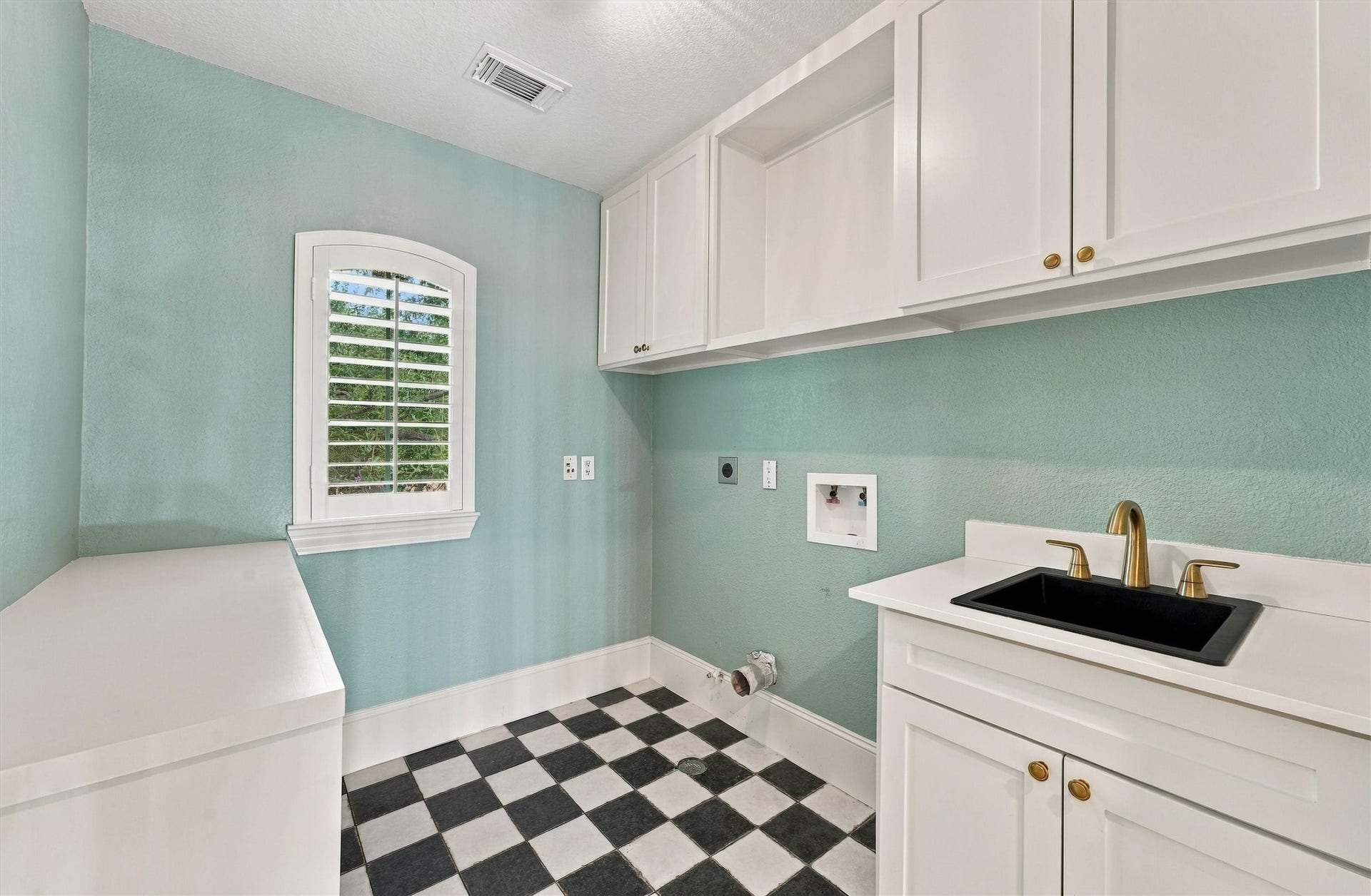 22415 Elizabeth Place Court, Katy, TX 77494 Second-floor laundry room with aqua walls, checkerboard floor, white cabinets, utility sink, and plantation shutters.