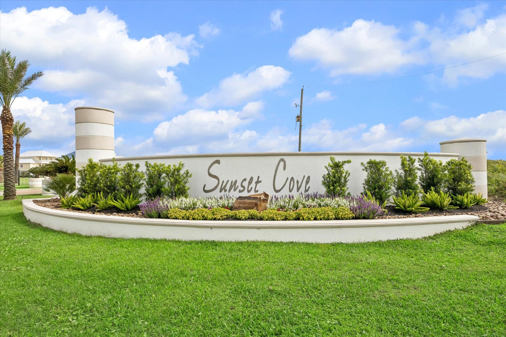 21205 Scissor Tail Lane, Galveston, TX 77554 Landscaped Sunset Cove signage gives the neighborhood a polished coastal entrance, with palms and layered plantings adding to the arrival. A clean first impression for a gated community built around beachside and bayside living.