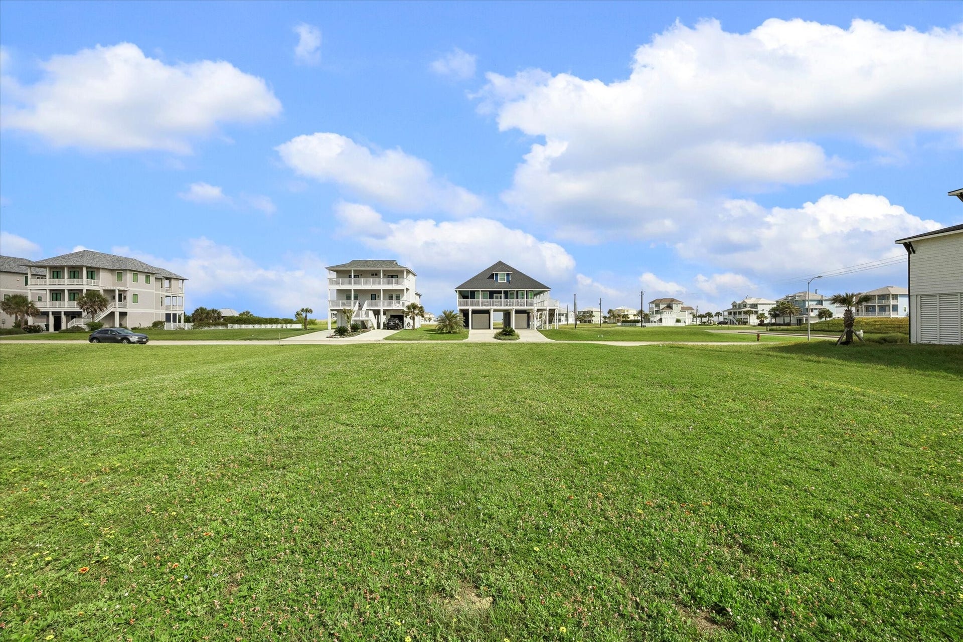 21205 Scissor Tail Lane, Galveston, TX 77554 Wide open green space surrounds the homesite, with neighboring coastal homes giving a clear sense of the setting and scale. A peaceful spot to plan a beach-area build with room to take in the sky, breeze, and neighborhood views.