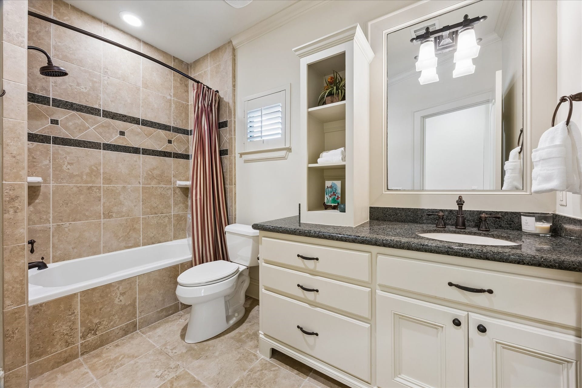 4037 Dumbarton Street, Houston, TX 77025 This bathroom features a tiled shower-tub combo, ample countertop space, and plenty of storage with built-in shelving and cabinetry. This bathroom serves secondary bedrooms #3 and #4.