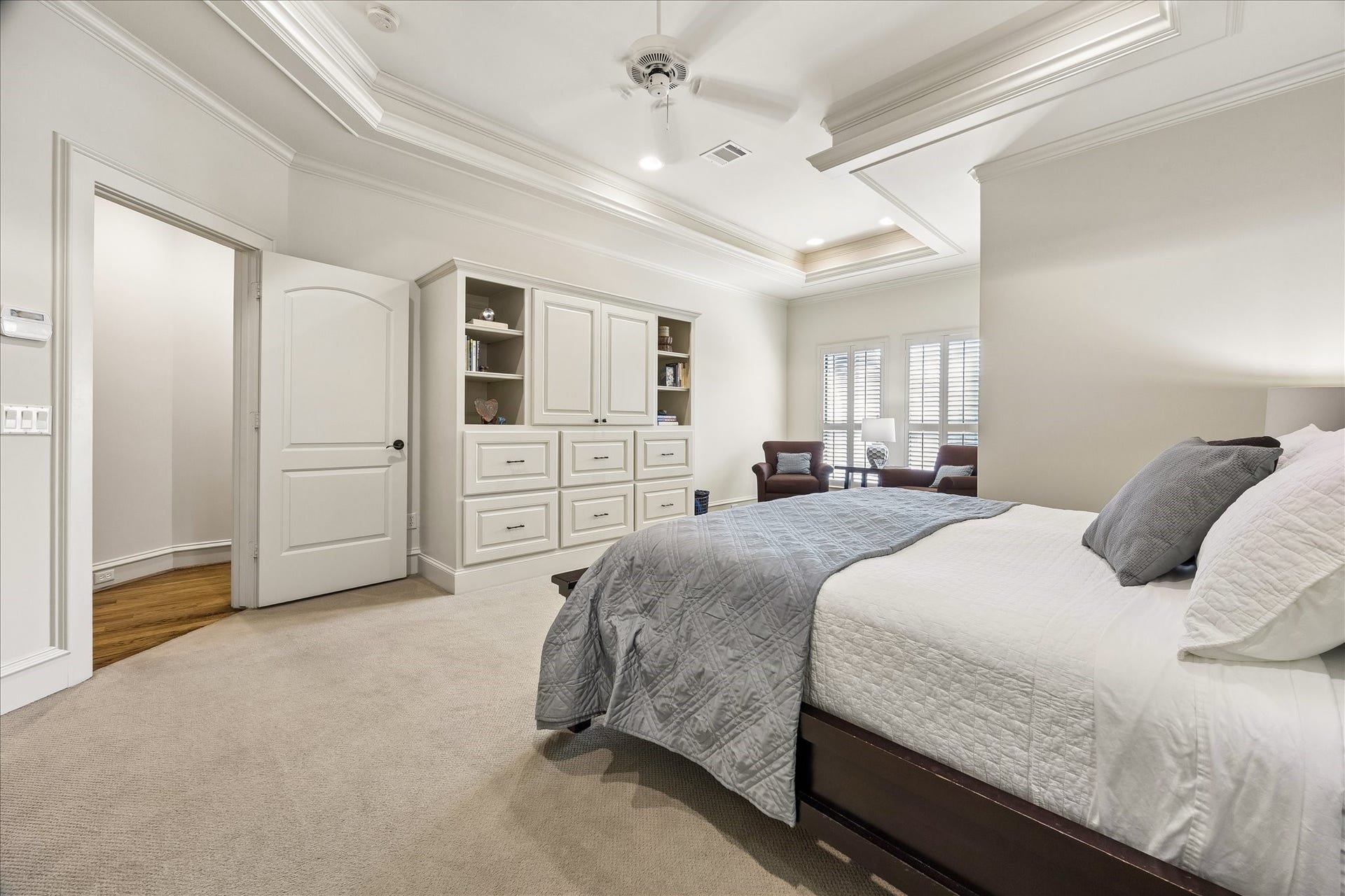 4037 Dumbarton Street, Houston, TX 77025 Spacious primary bedroom featuring elegant tray ceilings, ample built-in storage, and a cozy seating area by large windows.