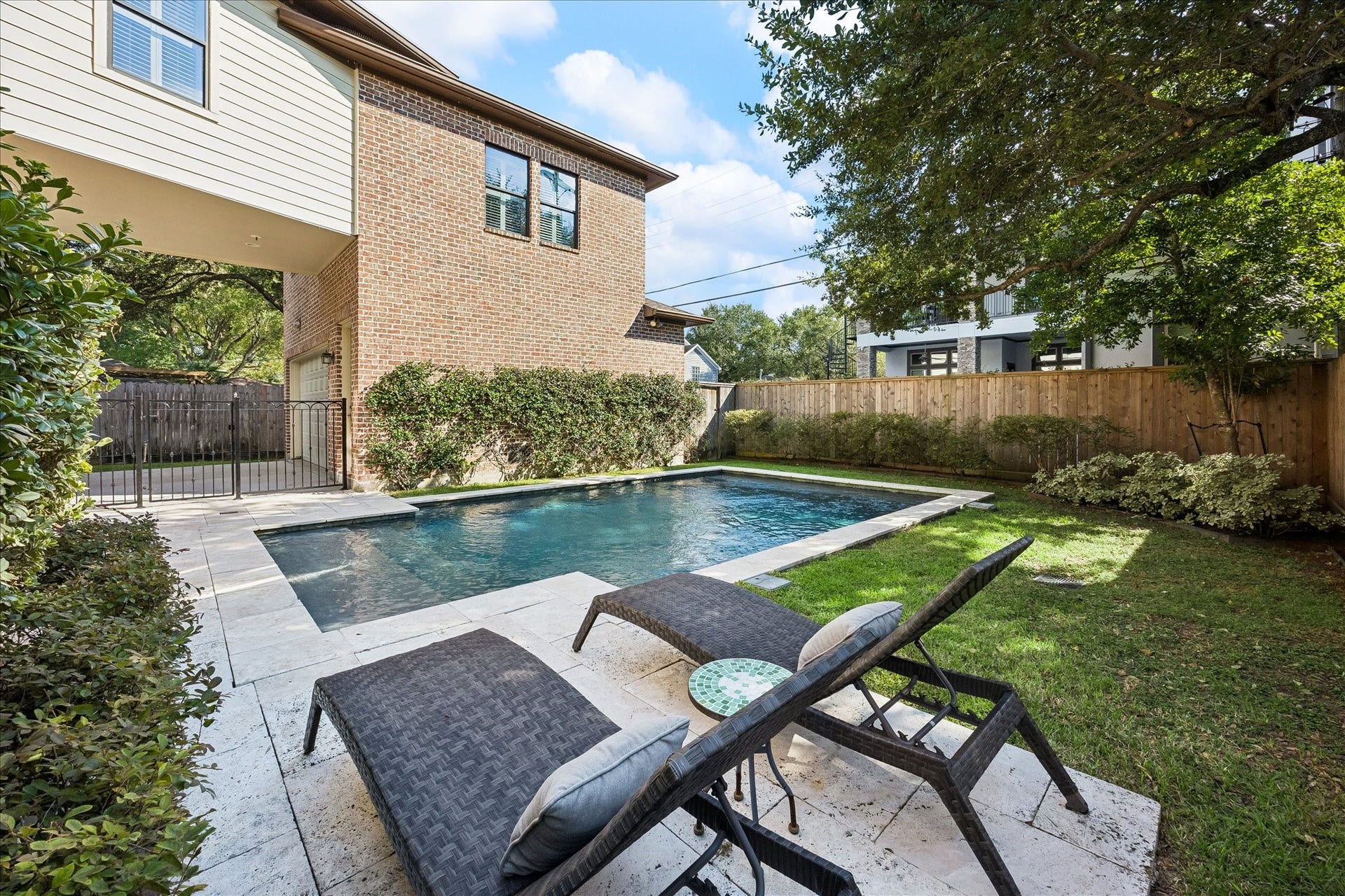4037 Dumbarton Street, Houston, TX 77025 Enjoy this backyard oasis featuring a sparkling pool surrounded by lush greenery and a spacious patio, perfect for relaxation and entertaining.