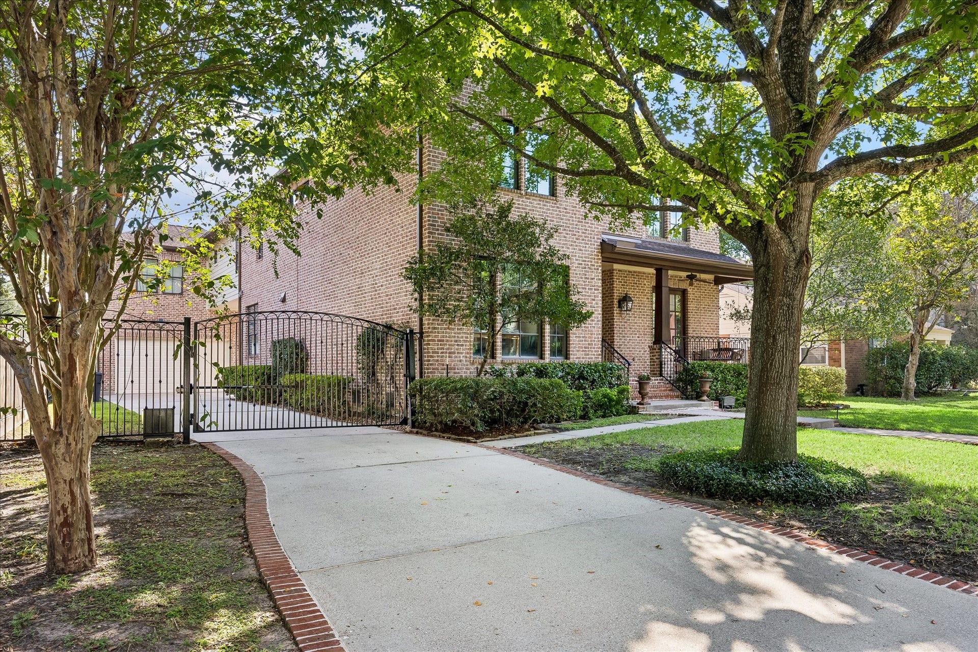 4037 Dumbarton Street, Houston, TX 77025 This beautiful brick custom home with a welcoming front porch, nestled among mature trees and lush greenery, features a gated driveway for added privacy and security.